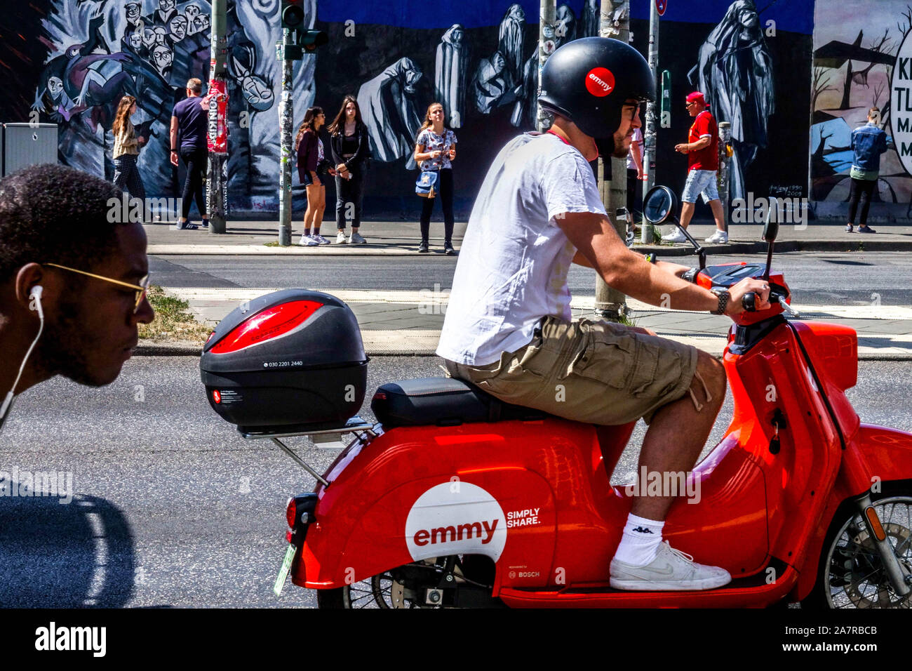 Berlin Wall, ein Mann auf Mietwagen Emmy vorbei in Muhlenstraße, East Side Gallery Deutschland Friedrichshain City Street Stockfoto