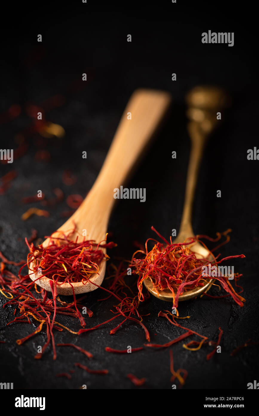 Safran Gewürze Threads in Löffel auf schwarzem Schiefer Tisch aus Stein. Safran Geschmack und die Färbung seasoning Zutat. Stockfoto