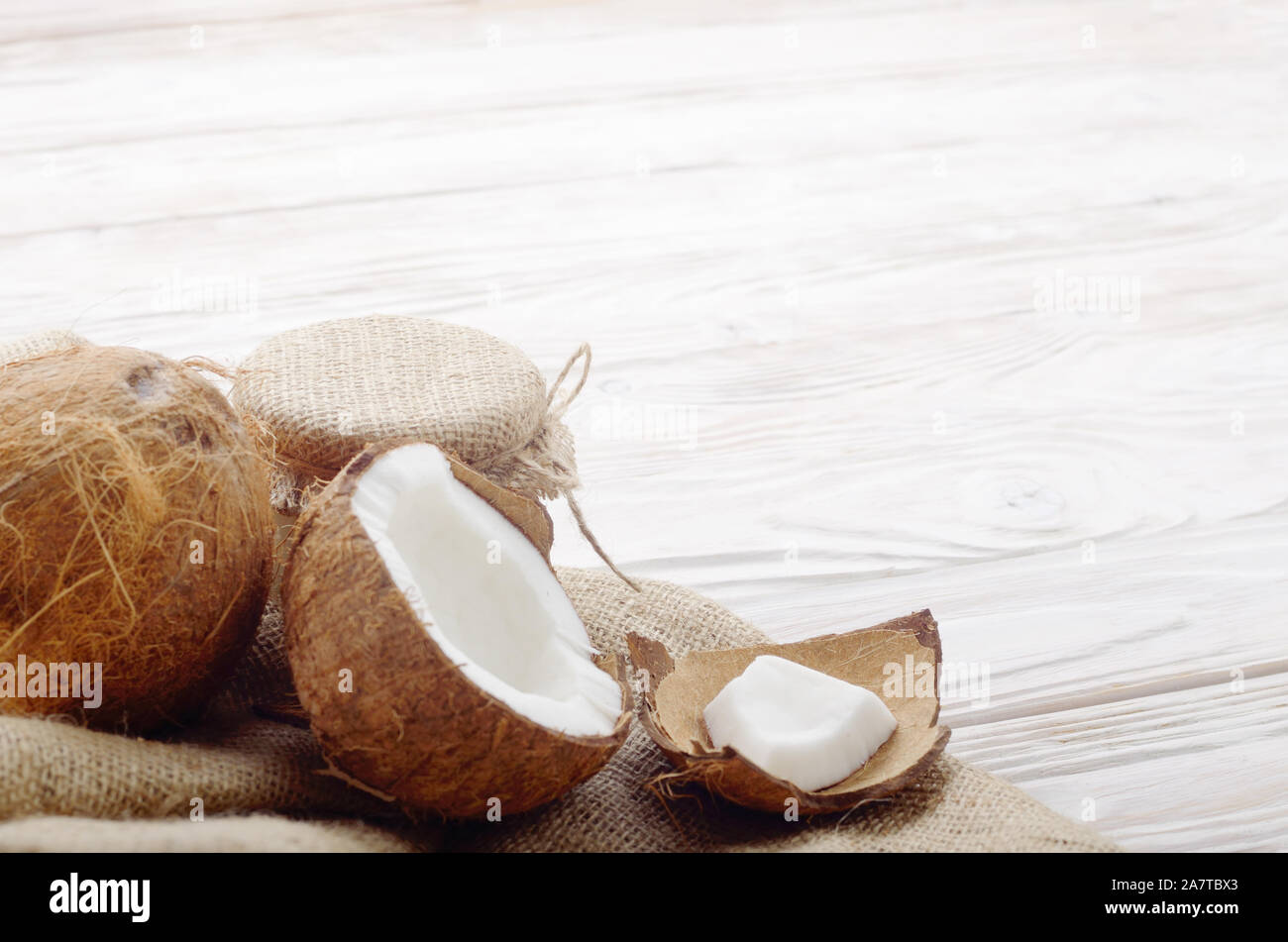 Coconut Shell mit Fleisch auf Hanf Sack auf weißen Küche aus Holz Tisch Stockfoto
