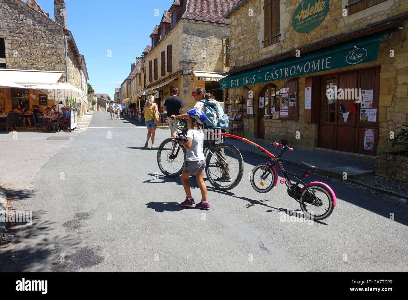 Domme, Frankreich vom 15. Juli 2019: Touristen, darunter eine Mutter und eine Tochter mit ihren Fahrrädern im Zentrum von Domme in der Region Dordogne Frankreich Stockfoto