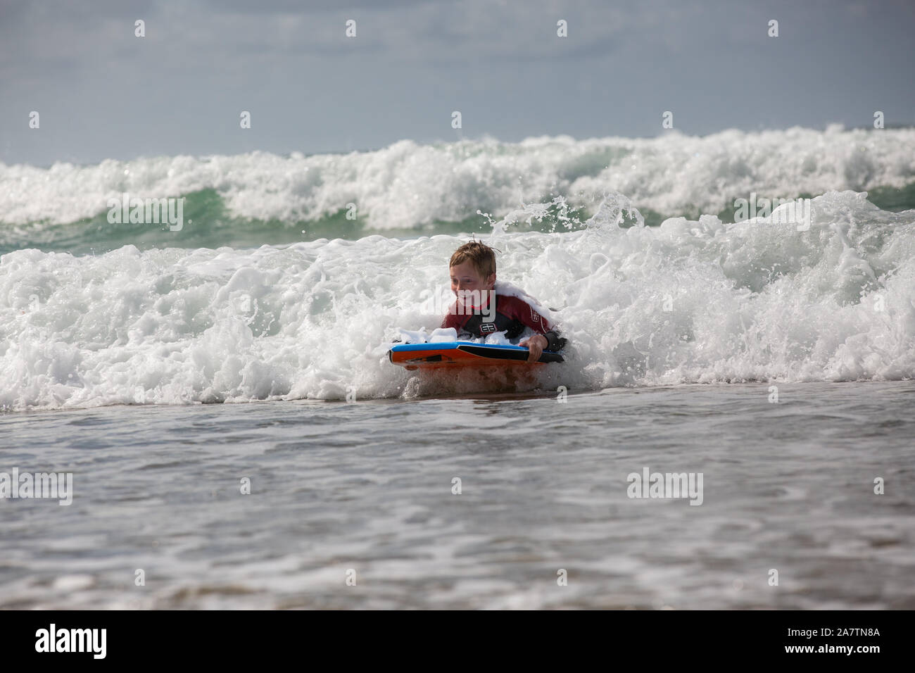 Ein Junge surfen am Strand, Pembrokeshire, Wales. Stockfoto