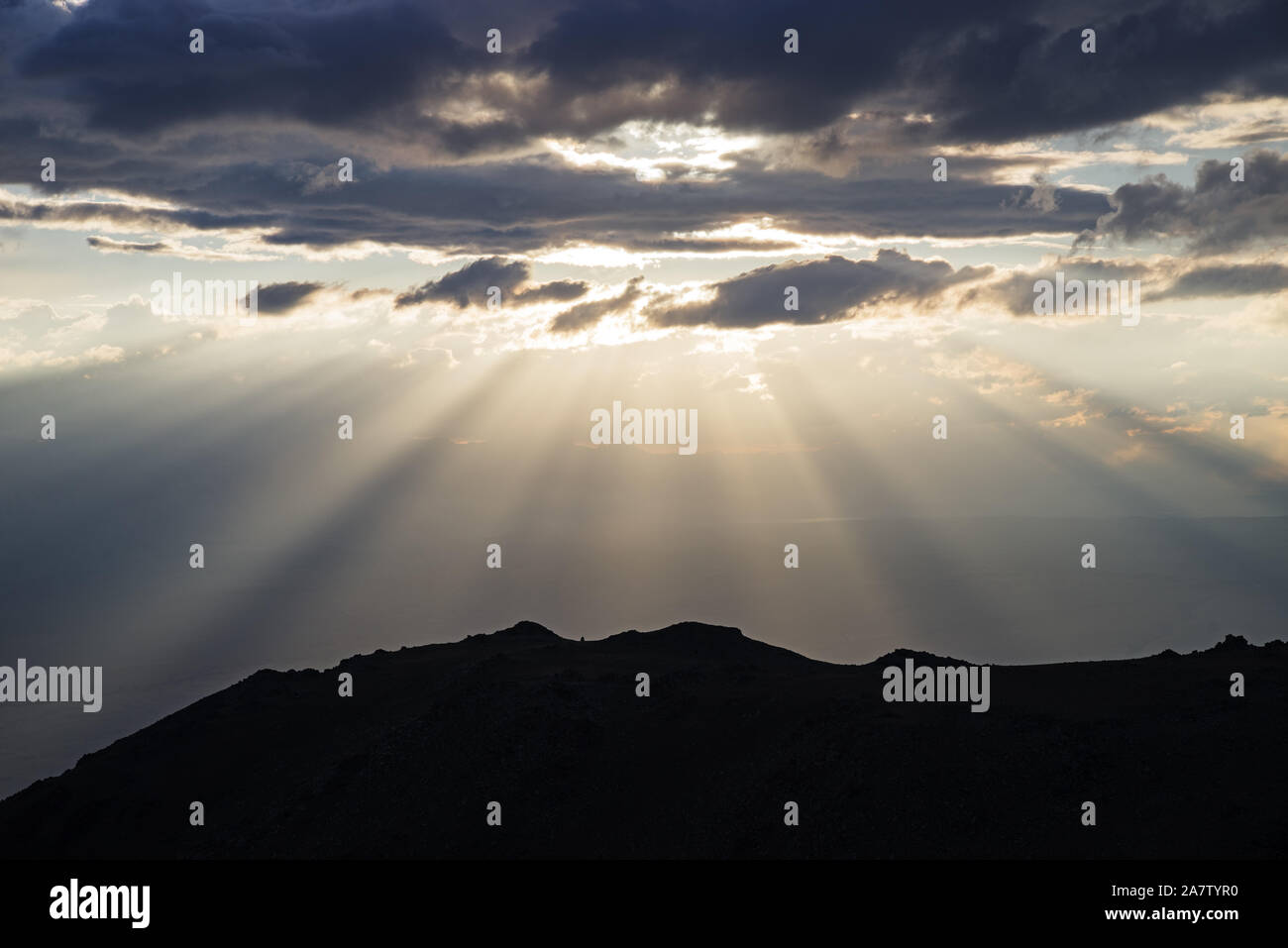 Sonnenstrahlen stream aus Wolken hinter einem Hügel Stockfoto