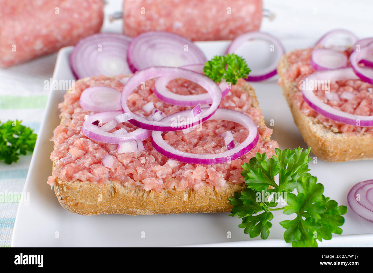 Deutsche essen mett Boden Schweinefleisch, Bun- und rohes Fleisch mit Zwiebeln und Petersilie, Nahaufnahme Stockfoto