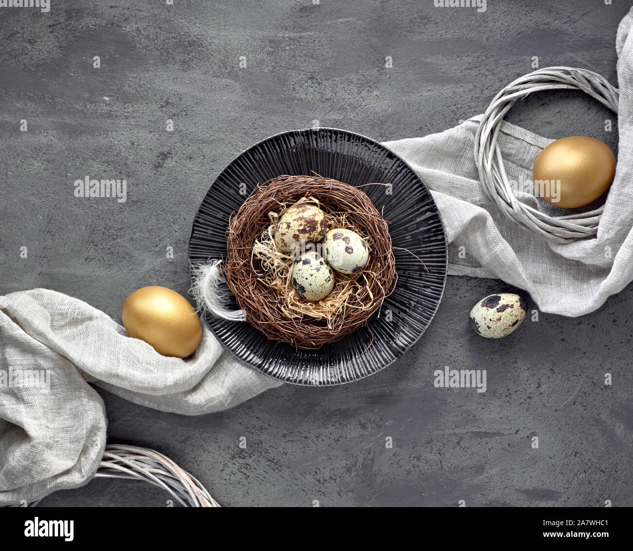 Ostern flach auf dunklem Hintergrund mit Golden bemalte Eier im Nest, Textil- und Wachteleier auf dunkel strukturierten Hintergrund. Bewusste consumpti Stockfoto