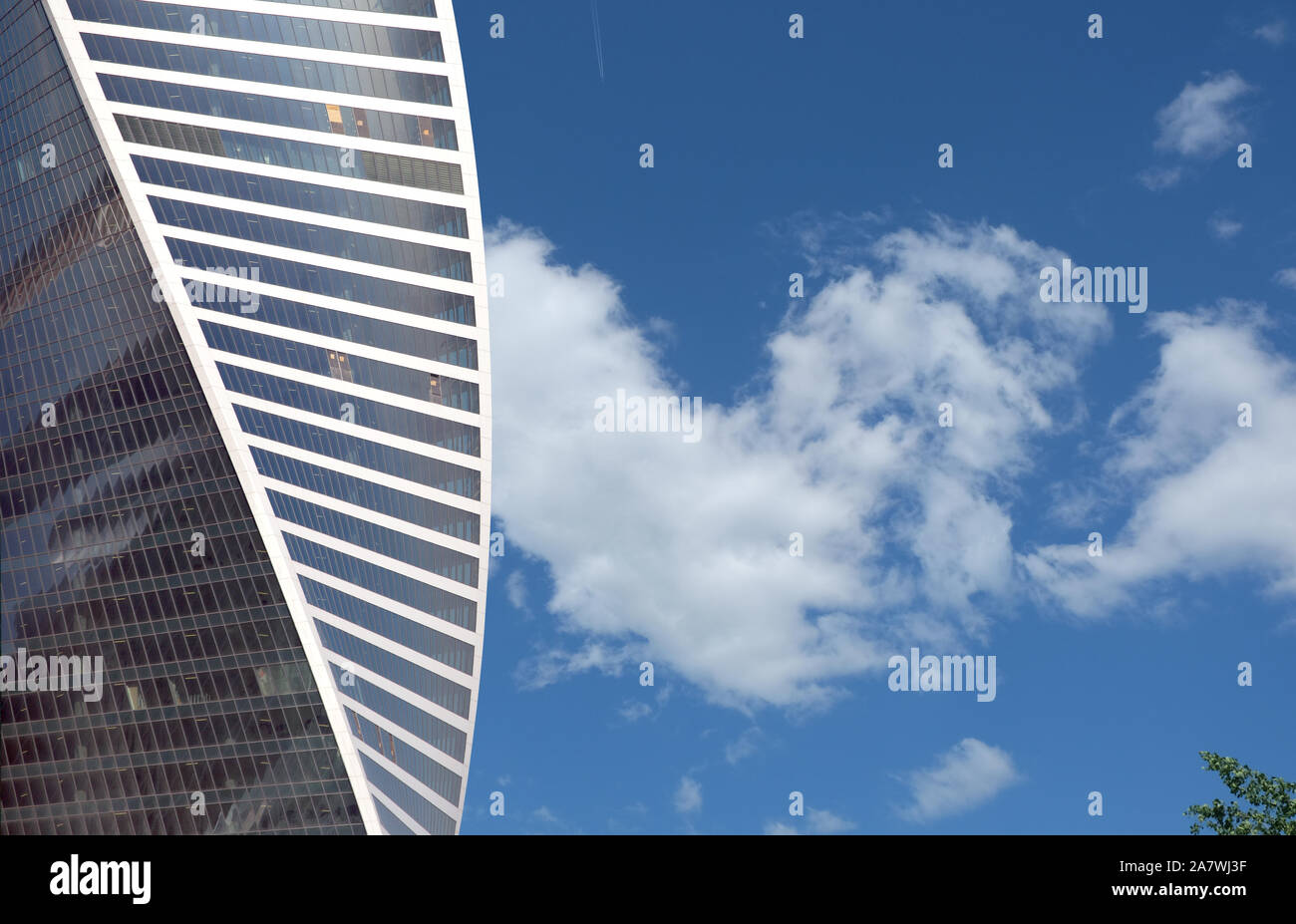 Angesichts der hohen modernen Spirale Office Tower Gebäude aus Glas und Metall über blauen Himmel mit Wolken im sonnigen Tag Stockfoto