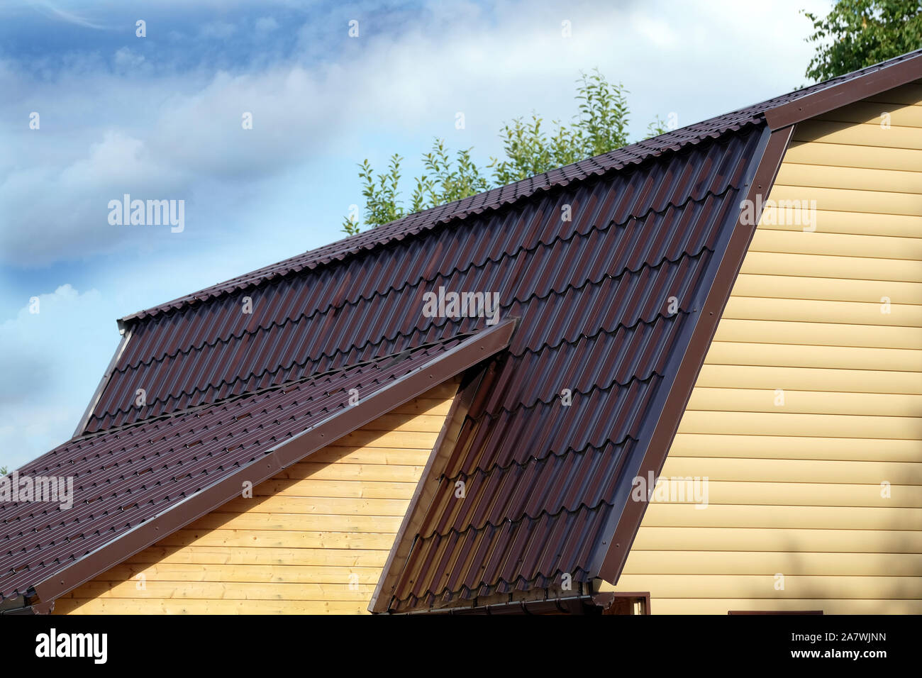 Braun Metall Dach der ländlichen Haus mit gelben Abstellgleis über blauen Himmel mit Wolken an einem sonnigen Tag Seitenansicht abgedeckt Stockfoto