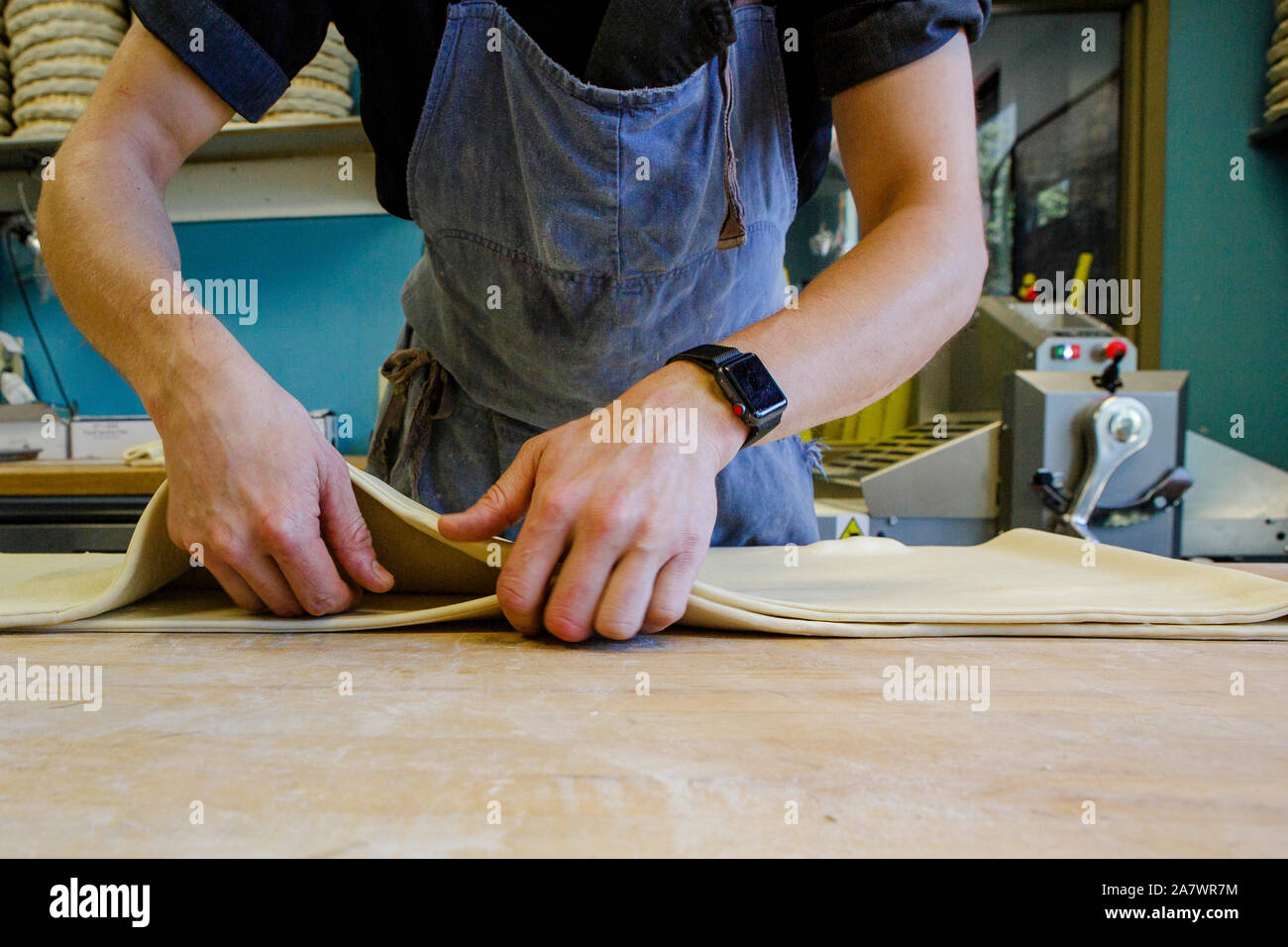 Nahaufnahme eines professionellen Bäcker arbeiten Teig auf der bemehlten Oberfläche Stockfoto