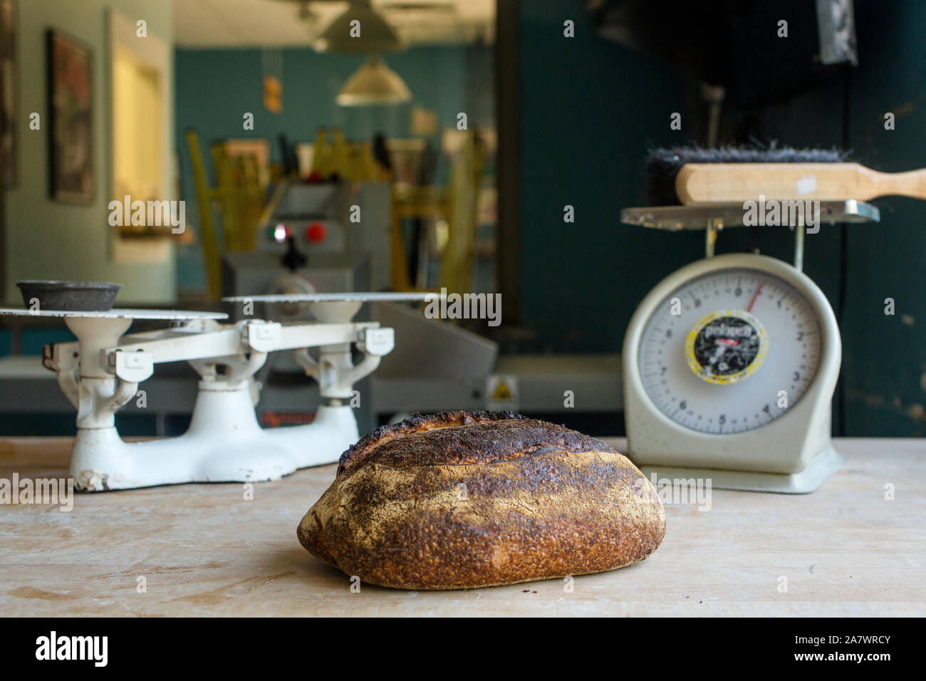 Frisch gebackenes Brot sitzt auf Bemehlten Zähler mit antiken Küchenwaagen Stockfoto
