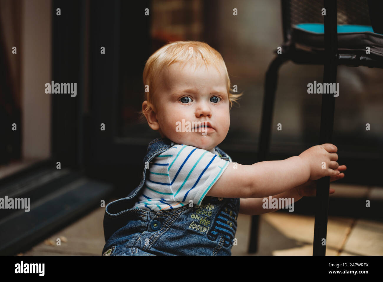 Sitzung baby boy Holding Stuhlbein besorgt schauen oder erschrocken Stockfoto