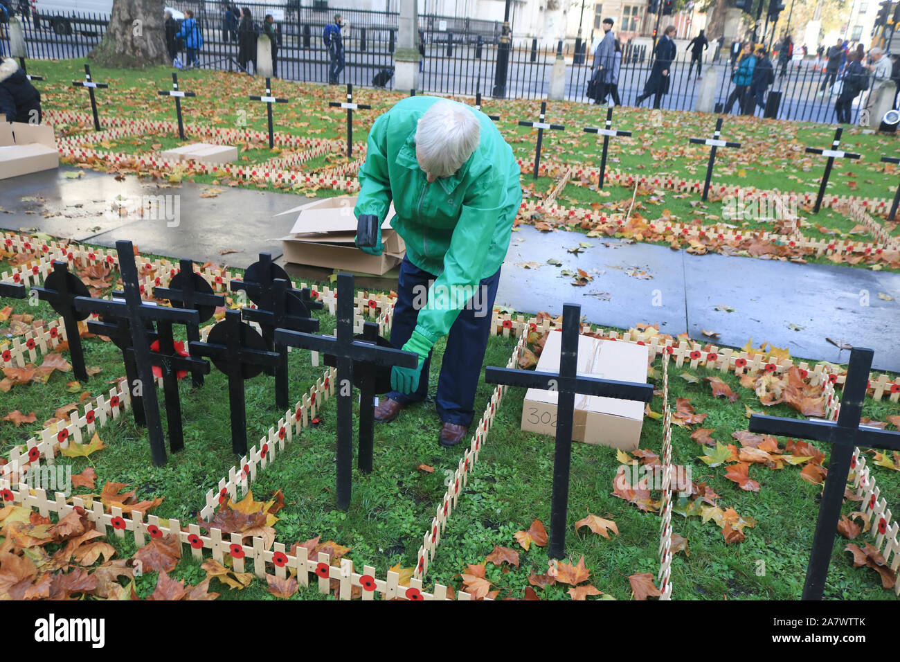 Ein freiwilliger Pflanzen Kreuze in Regimental Grundstücke außerhalb der Westminster Abbey vor der Erinnerung gedenken, der am Sonntag statt finden wird, den Gefallenen der Britische und Commonwealth Soldaten und Frauen der Konflikte der Vergangenheit ehren. Stockfoto