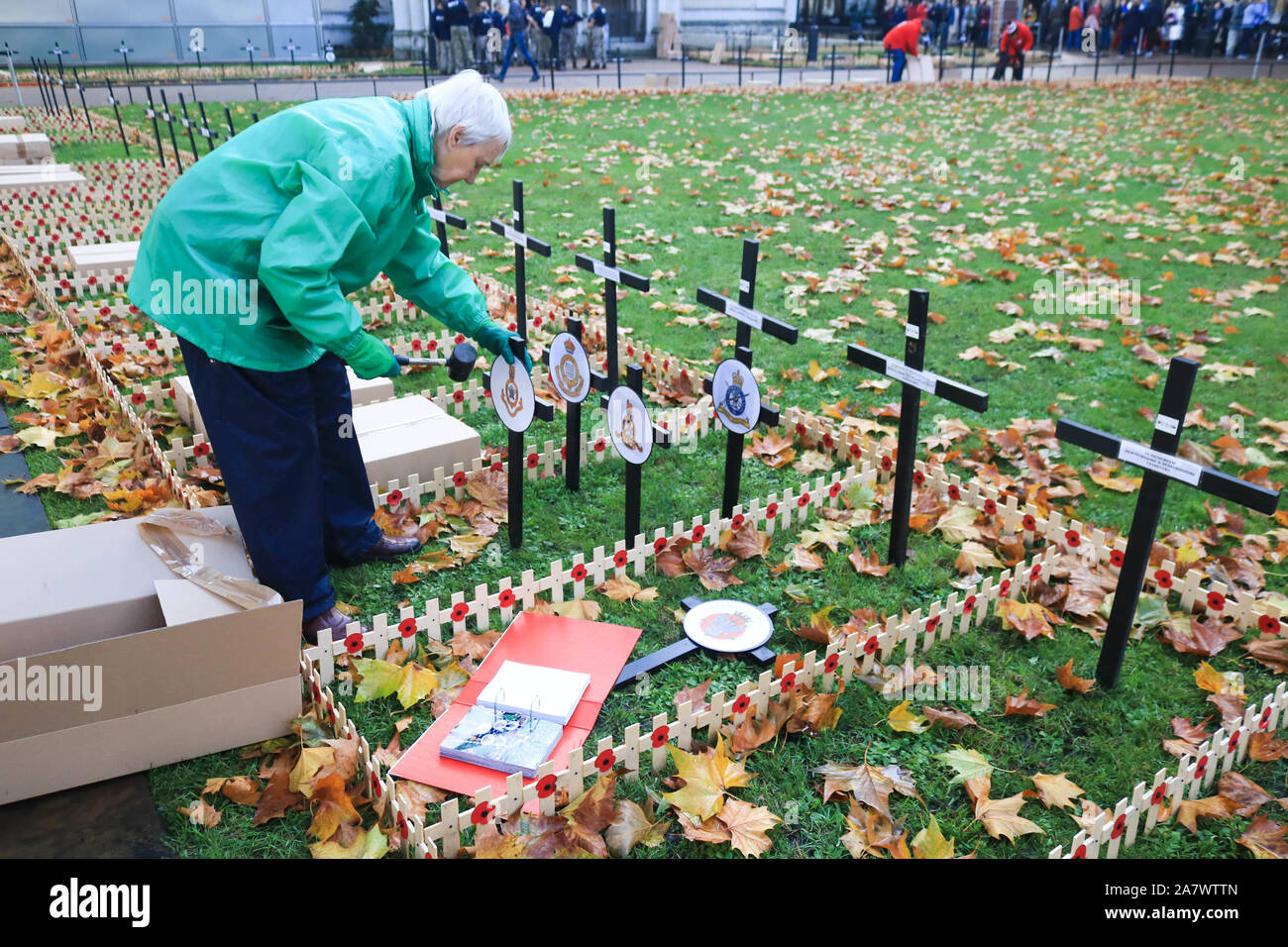 Einen freiwilligen aus British Legion Pflanzen kreuzt außerhalb der Westminster Abbey vor der Erinnerung gedenken, der am Sonntag statt finden wird, den Gefallenen der Britische und Commonwealth Soldaten und Frauen der Konflikte der Vergangenheit ehren. Stockfoto