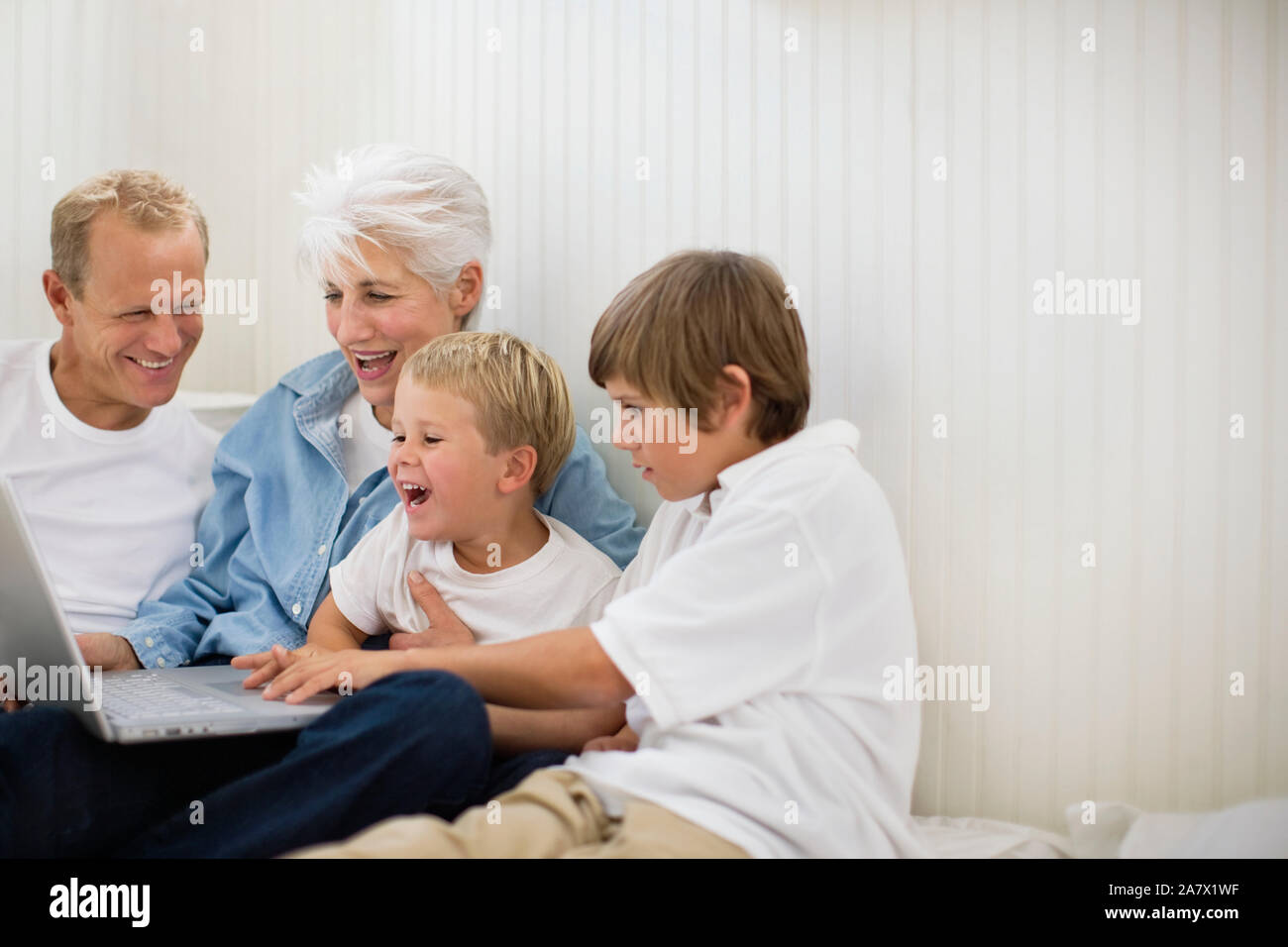 Mehrere Generationen der Familie auf dem Boden sitzend auf einem Laptop. Stockfoto