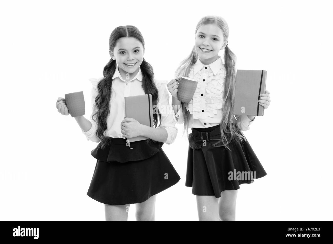 Nehmen Sie sich ein paar Minuten Pause aus ihren Büchern. Wenig Schülerinnen in Tee mit Milch für die Pause. Kleine Schule Kinder holding Tassen Essenspause. Nette Mädchen genießen Schule brechen. Stockfoto