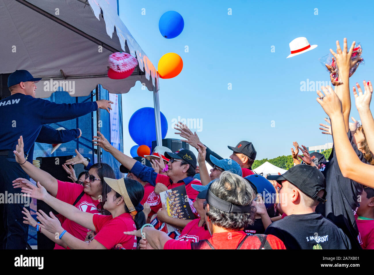 Anaheim, CA/USA - Nov 3, 2019: Freiwillige werfen Hüte und andere Goodies von der Bühne auf die aufgeregte Masse unten. Hände greifen für die Preise. Stockfoto
