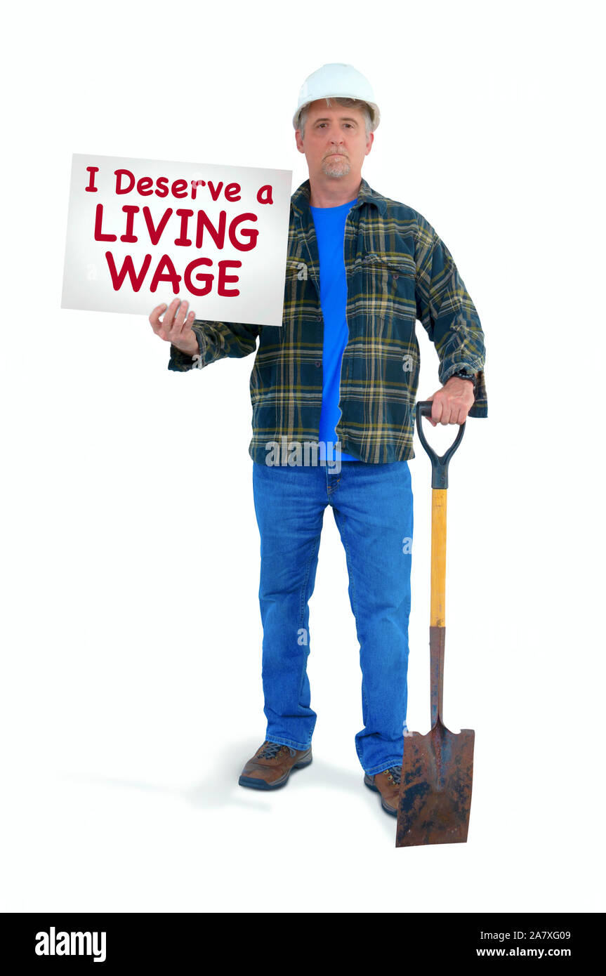 Blue collar Bauarbeiter Mann in einem weißen harten Hut mit Schaufel, manuelle Arbeit mit einem Schild, dass ich verdienen eine existenzsichernde Löhne zu kämpfen, sta Stockfoto