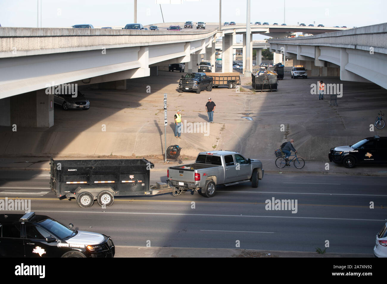 Arbeitnehmer aus dem Texas Highway Department Reinigung bis eine obdachlose Feldlager auf öffentlichen Vorfahrt unter einer Autobahnbrücke in Austin in Texas reg bestellt. Greg Abbott. Stockfoto