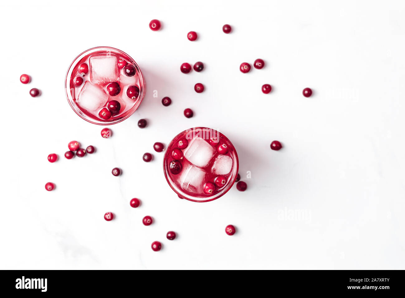 Cranberry Cocktail in Kristall Gläser mit Eis mit Beeren auf weißem Hintergrund hellem Marmor dekoriert. Kopieren Sie Platz. Flach Stil. Stockfoto