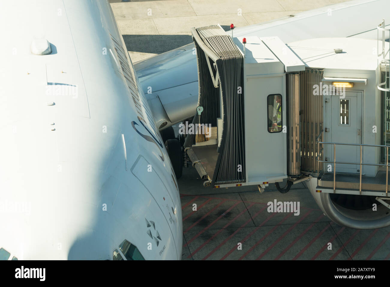 Anschließen oder Anbringen einer Fluggastbrücke oder PBB zu einer Tür von einem wartenden Flugzeug oder Flugzeug auf der Rollbahn am Flughafen Stockfoto