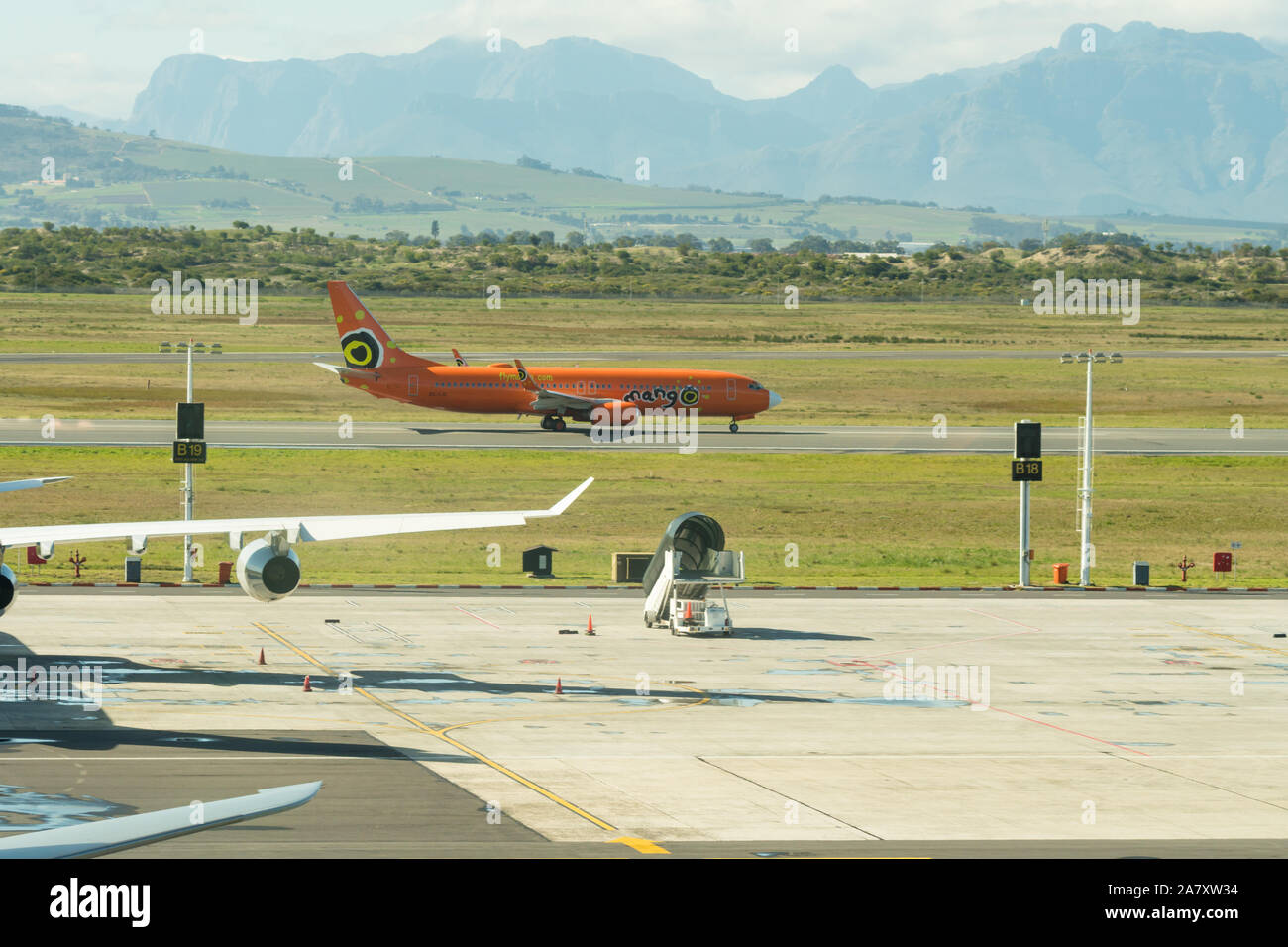 Mango airlines Flugzeug, das ist eine kostengünstige inländische Carrier auf der Start- und Landebahn am Flughafen Kapstadt vor dem Hintergrund der Berge im Winter Stockfoto