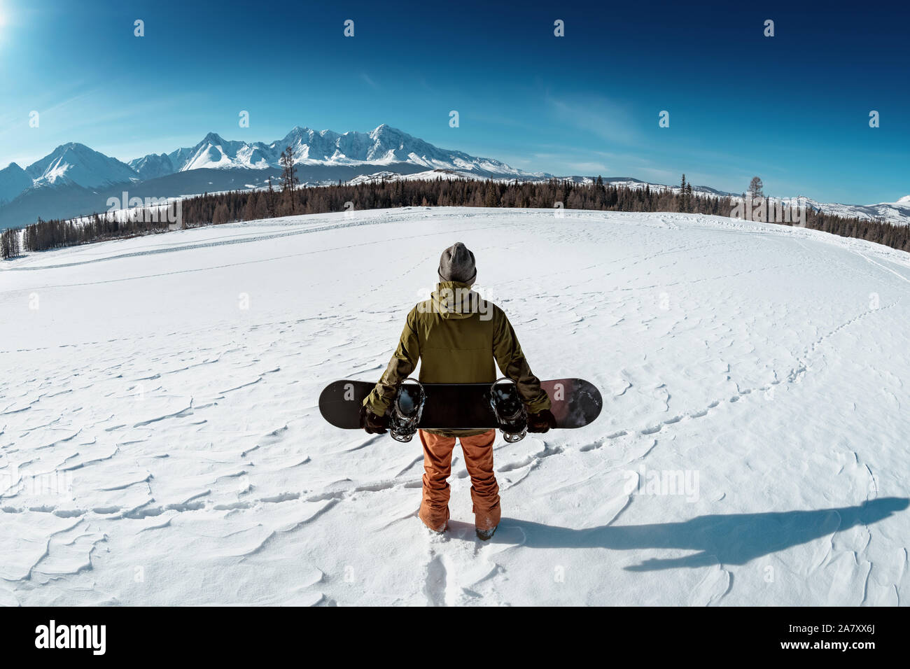 Snowboarder steht mit Snowboard gegen Berge. Backcountry Konzept Stockfoto