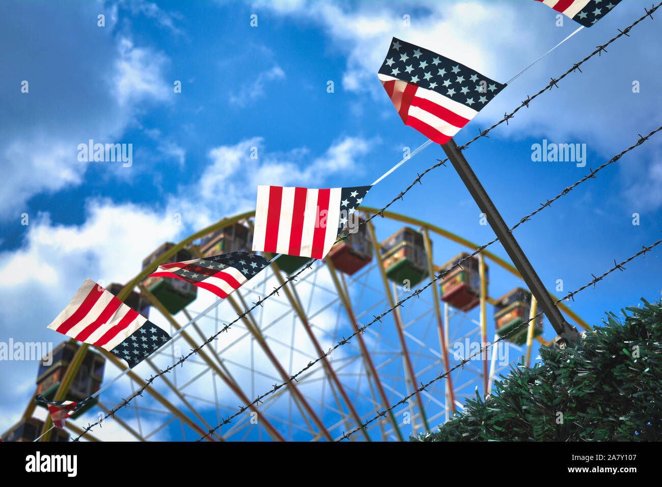 Vereinfachte Fahne mit amerikanischen Farben mit roten Streifen und weiße Sterne auf blauem Hintergrund hängen ein Stacheldrahtzaun mit Riesenrad in zurück Stockfoto