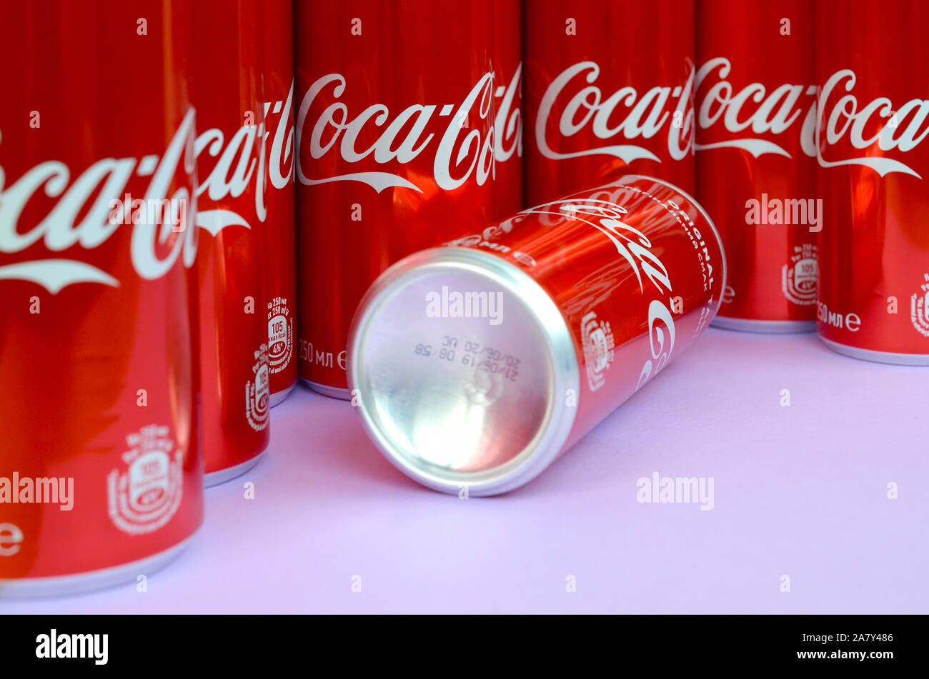 KHARKOV, UKRAINE - OKTOBER 2, 2019: Coca-Cola Logo auf Aluminiumdosen und auf Licht lila Hintergrund platziert. Die meisten berühmten Soda drink Produkt comp Stockfoto