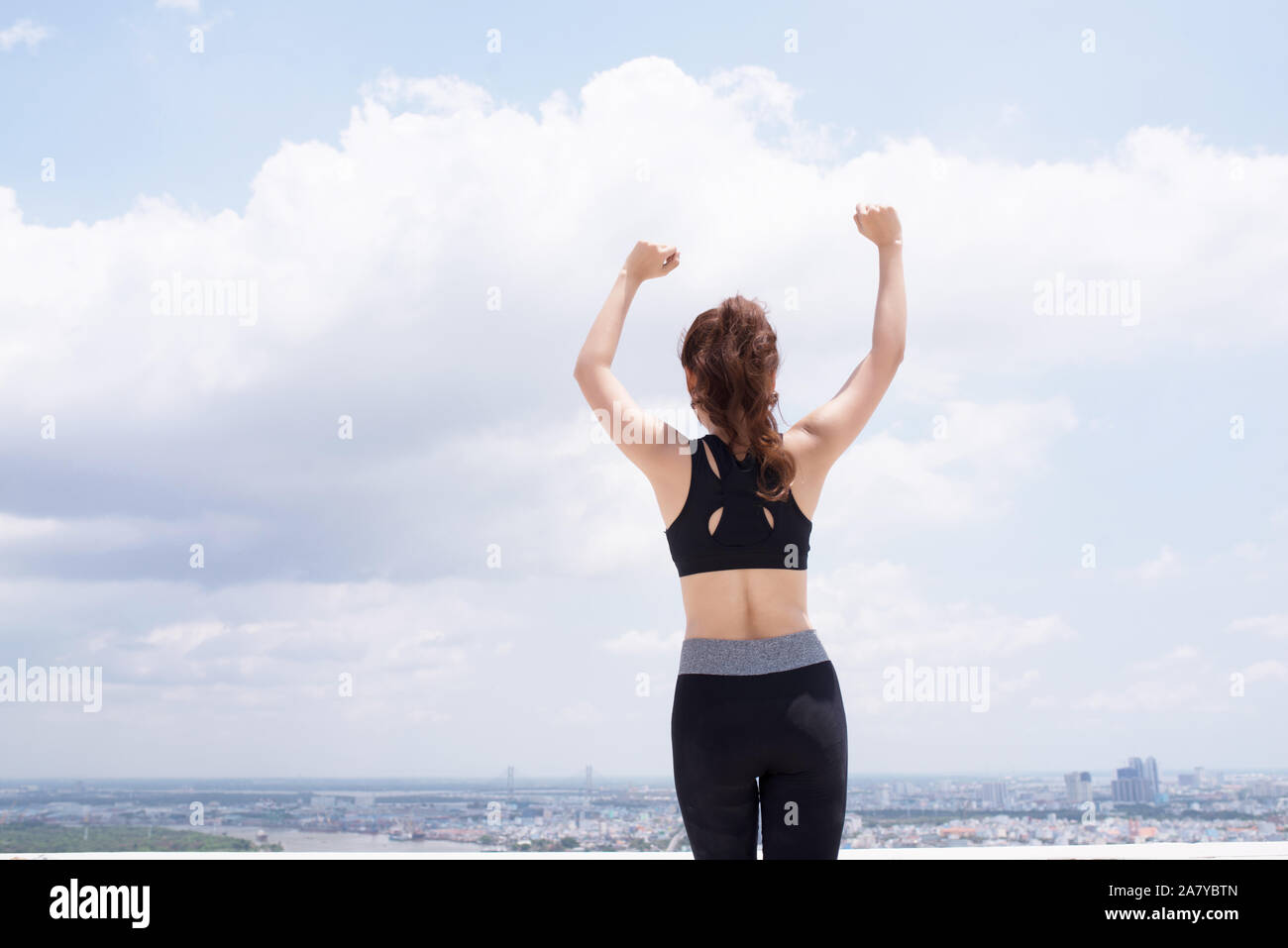 Ansicht der Rückseite des schönen Frau in stilvolle Sportswear stehend auf dem Dach. Nach dem Training Stockfoto