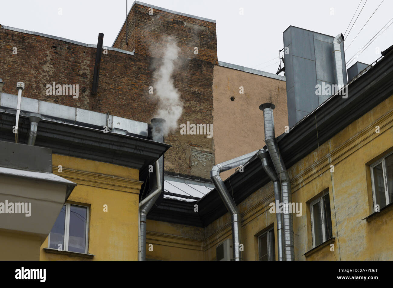 Die Wände der alten Häuser mit silbrig-Rohre Lüftungsanlage mit Rauch über einem der Rohre Stockfoto