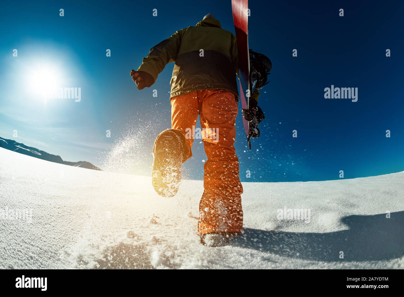 Snowboarder geht bergauf mit Snowboard in den Händen. Backcountry Skiing Konzept Stockfoto