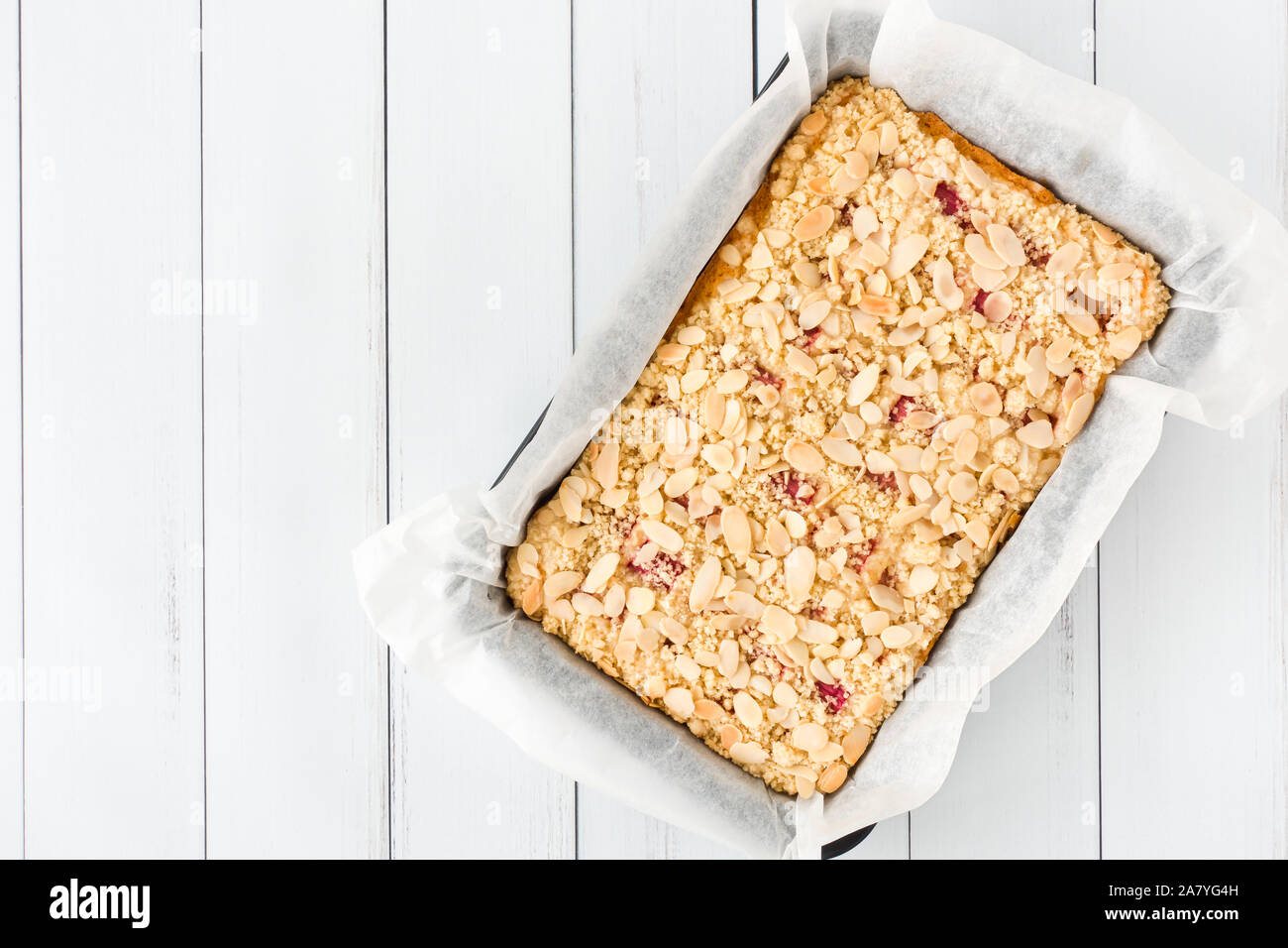 Rhabarber Kuchen in einem Backblech mit Backpapier auf weißem Holz panel Hintergrund mit Kopie Raum gesäumt. Ansicht von oben. Stockfoto