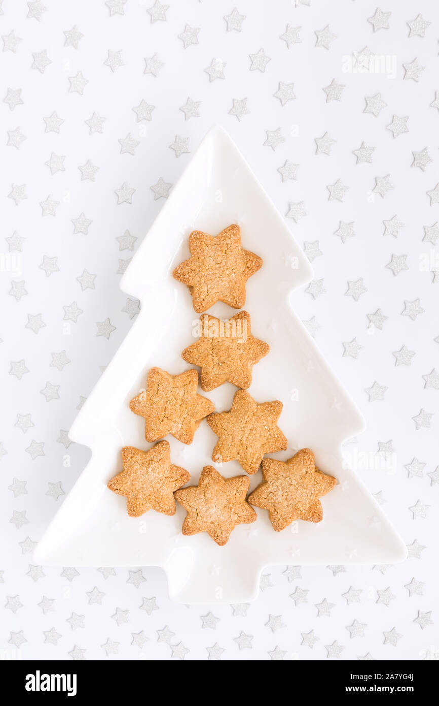 Sternförmige hausgemachtes Weihnachtsgebäck am baum-förmige Platte und Silver Star Konfetti auf weißem Hintergrund mit kopieren. Ansicht von oben. Stockfoto