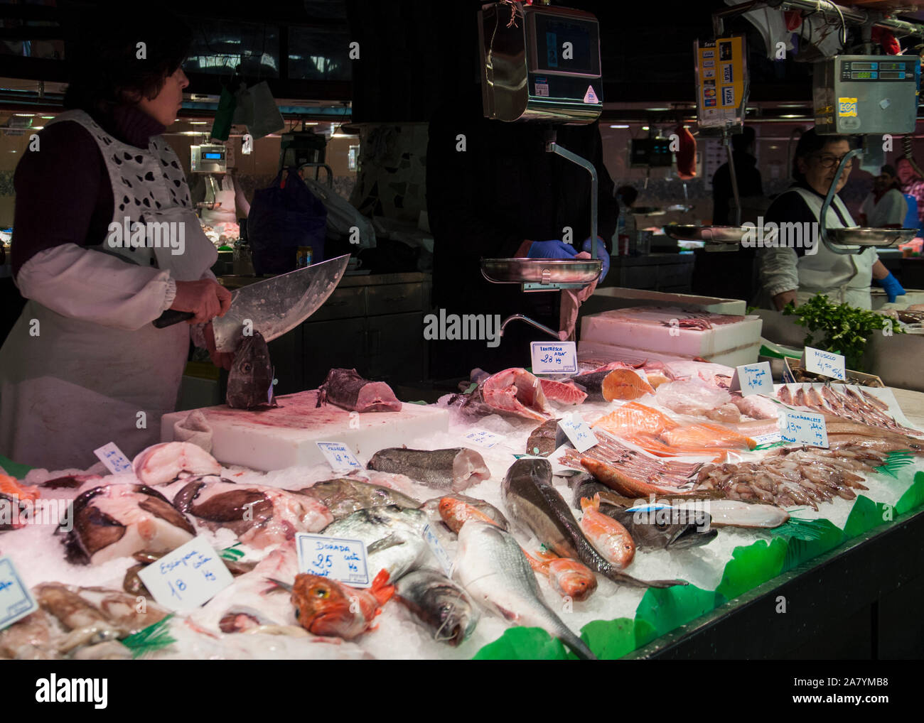 Barcelona, Spanien - 3. Mai 2017: Mercado de La Boqueria/La Boqueria Markt. Ein fischhändler Schneiden ein Fisch Kopf an einen gut sortierten Fische Marktstand. Stockfoto