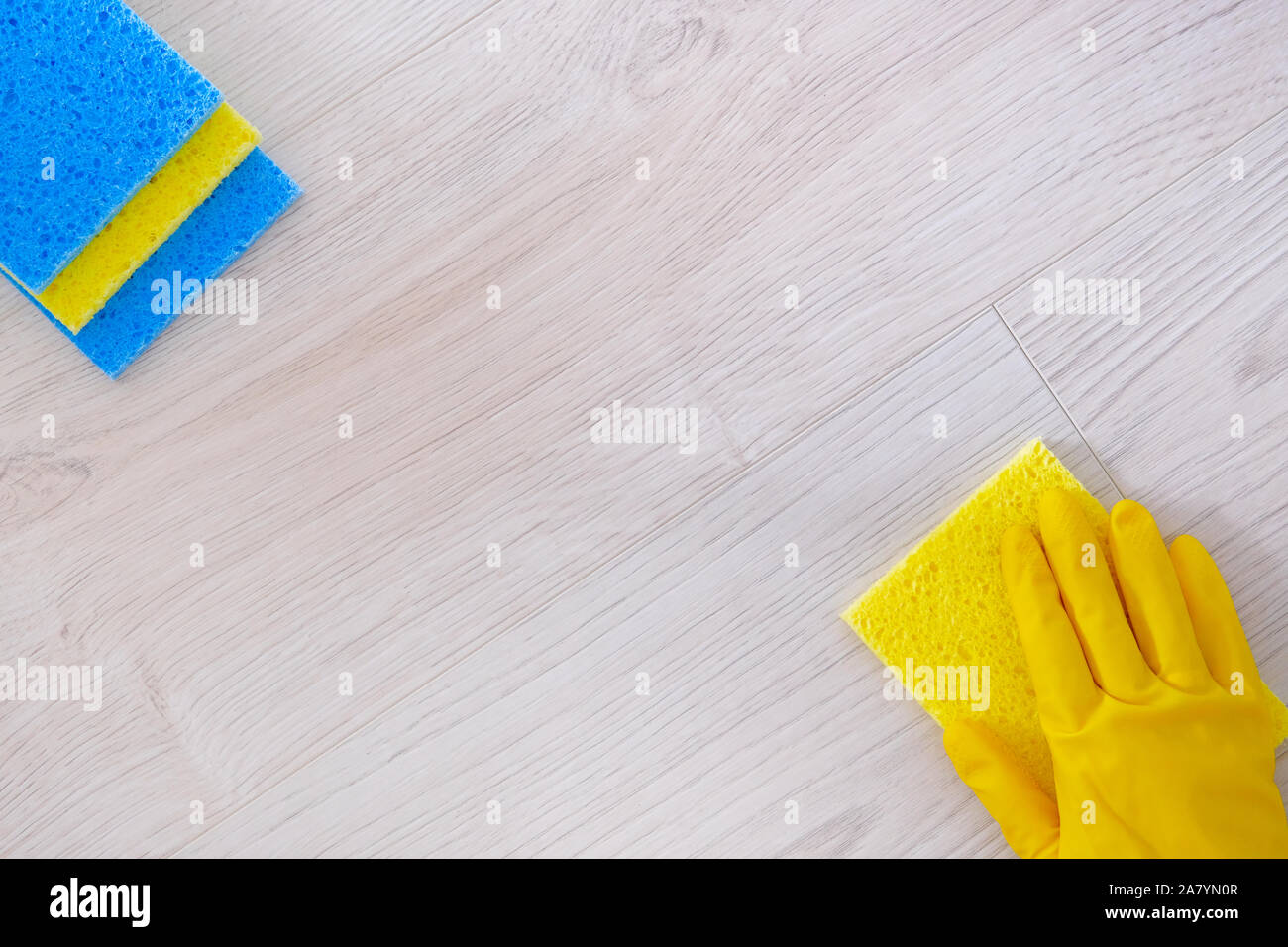 Ansicht von oben. Hand in gelb Gummi Schutzhandschuh Reinigung Parkettboden mit Rag zu Hause. Hausarbeit und die allgemeine Ordnung und Sauberkeit. Stockfoto