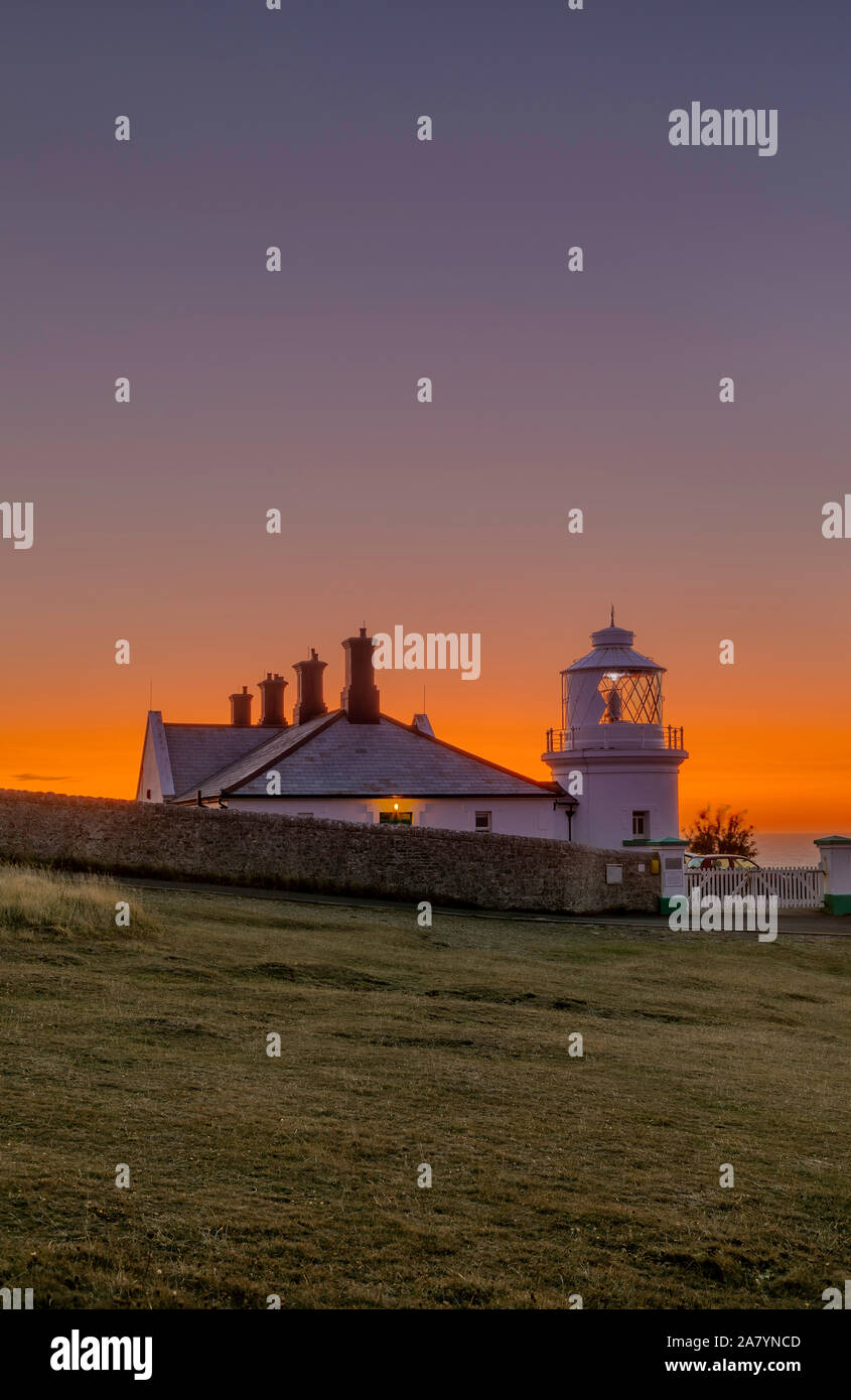 Swanage, Dorset England Schöne orange leuchten, kurz vor Sonnenaufgang, an Amboss Point Lighthouse Stockfoto