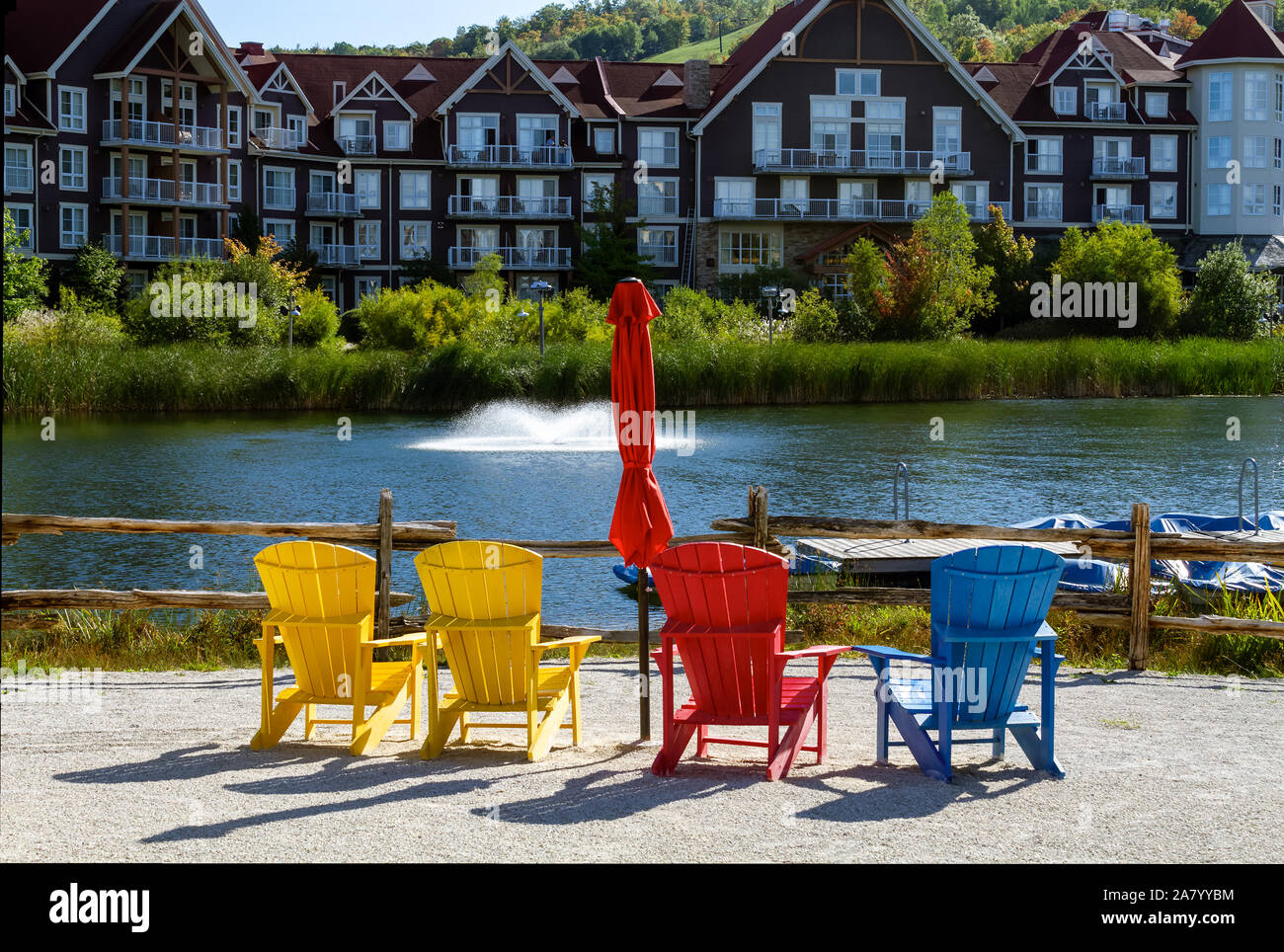 Bunte Muskoka Stühle auf Mühle Teich Dock im Herbst im Blue Mountains Dorf Stockfoto