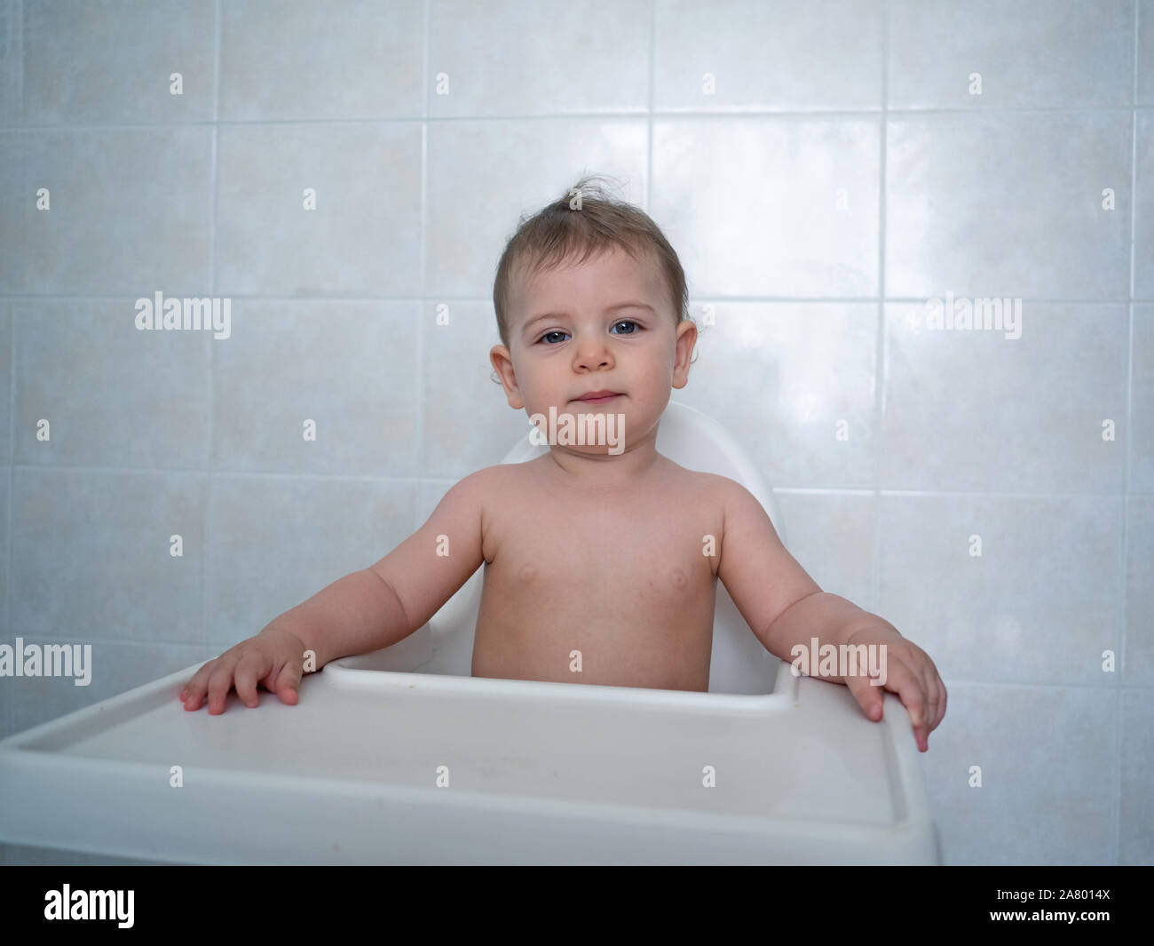 1 Jahr alte Hündin Baby sitzt auf einem hohen Stuhl warten auf Ihre Mahlzeit Stockfoto