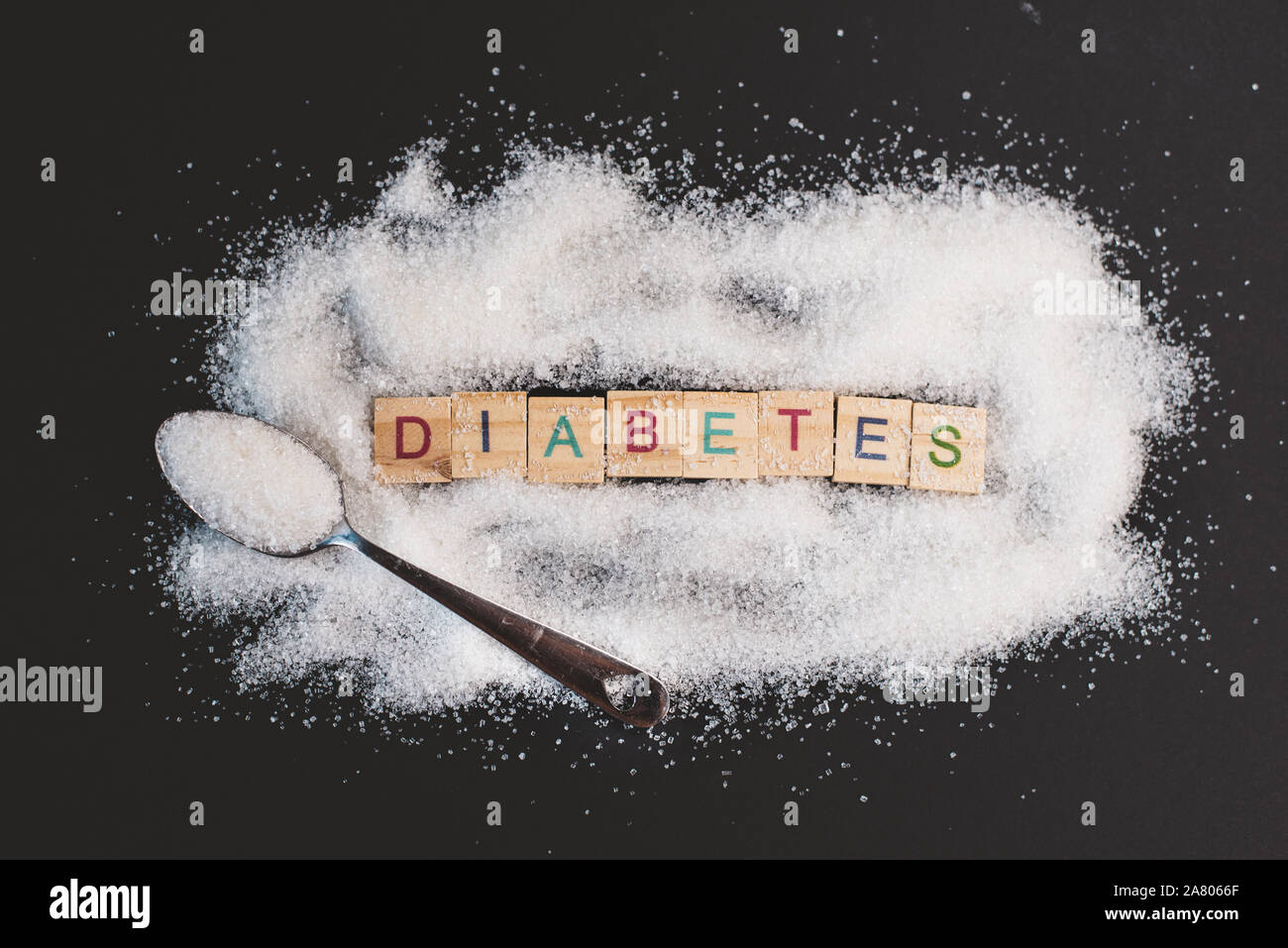 Haufen Zucker mit Wort DIABETES auf schwarzem Hintergrund. Konzept der Diabetes, Gesundheit und ungesundes Essen Stockfoto