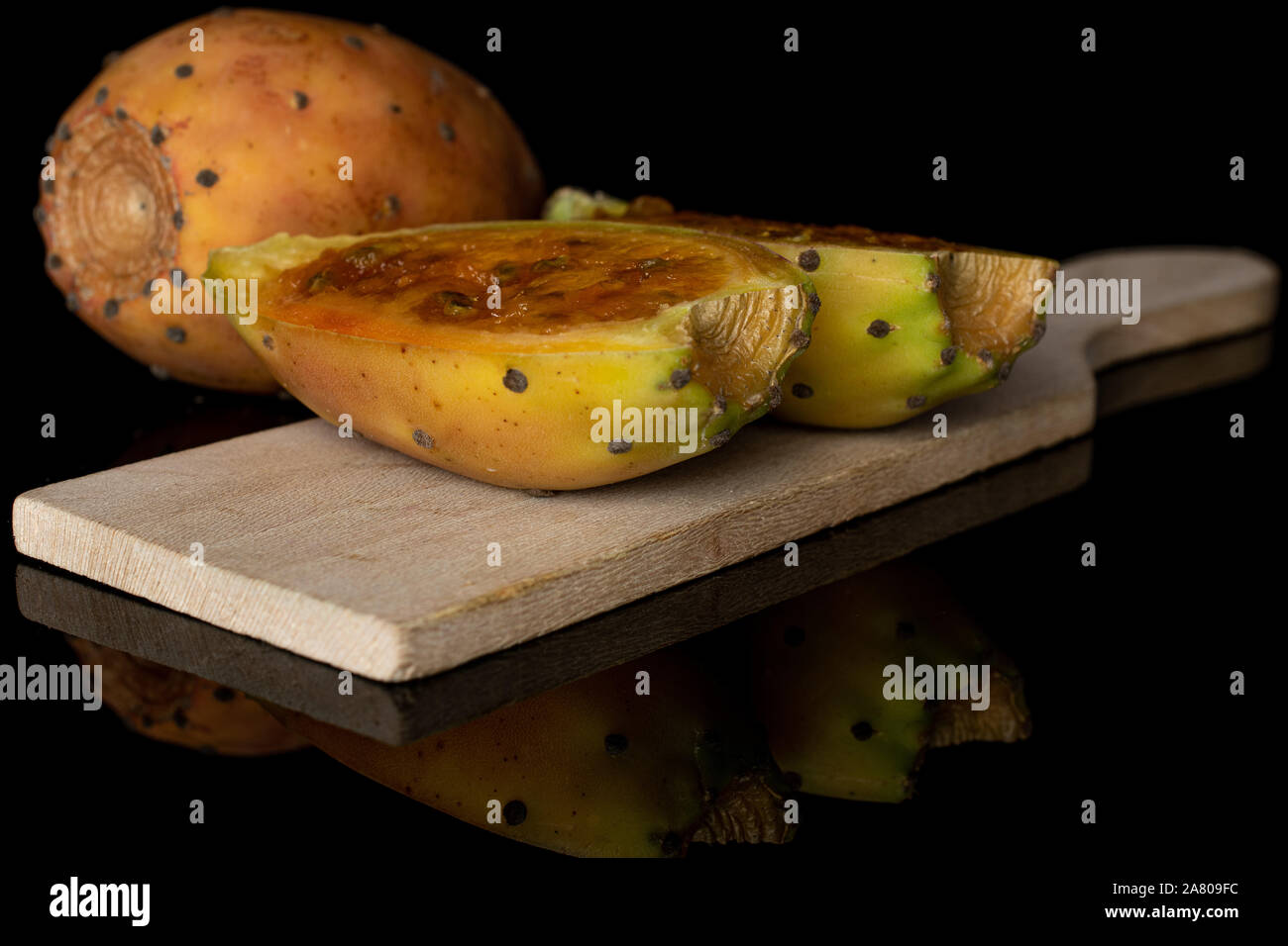 Gruppe von einer ganzen zwei Hälften der stachelige grüne Opuntia auf Holz Schneidebrett auf schwarzem Glas isoliert Stockfoto