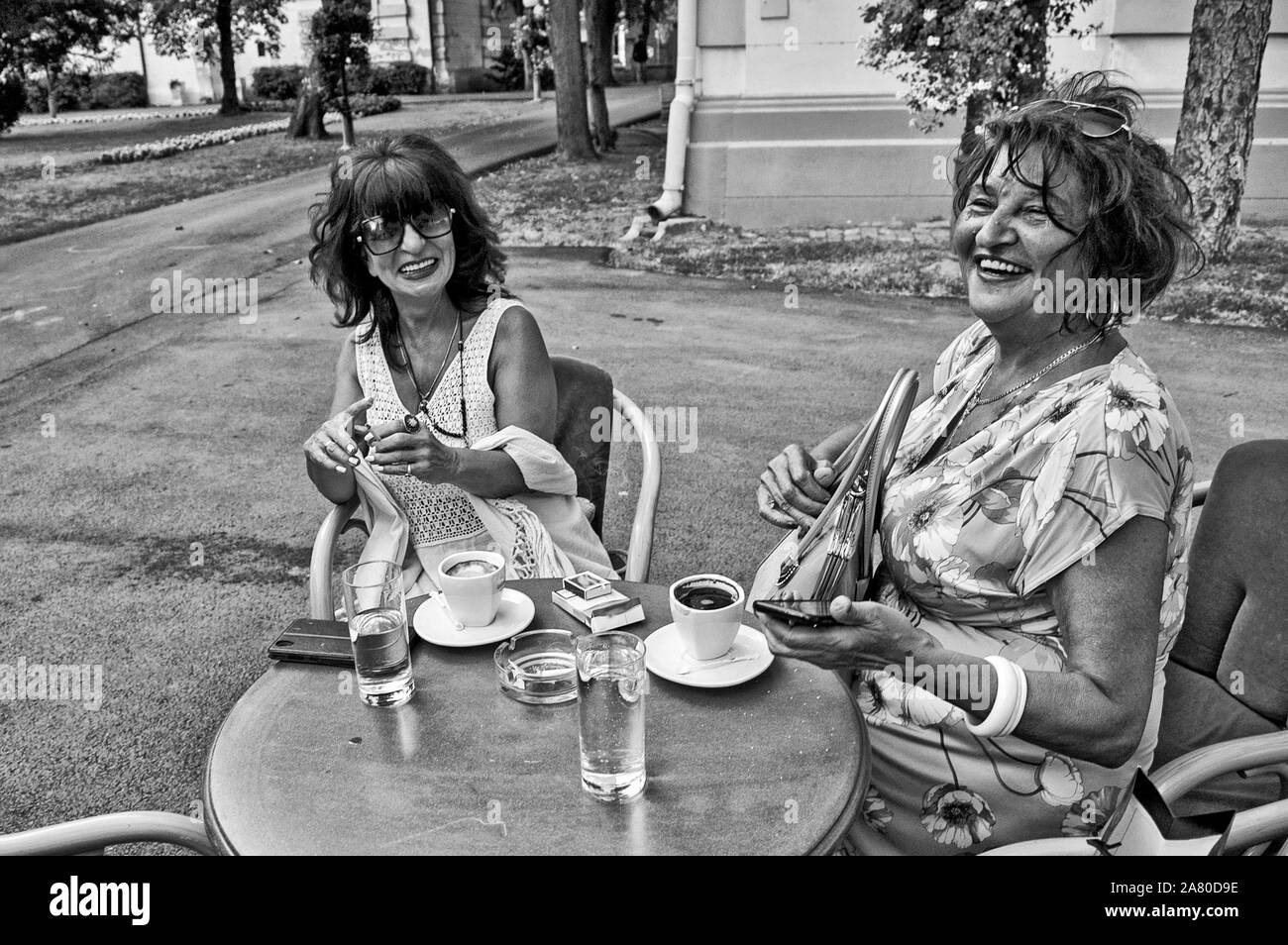 Treffen an einem Sommergarten Restaurant mit zwei Frauen über Kaffee und Zigaretten. Sie haben sich schon seit langer Zeit gesehen. Stockfoto