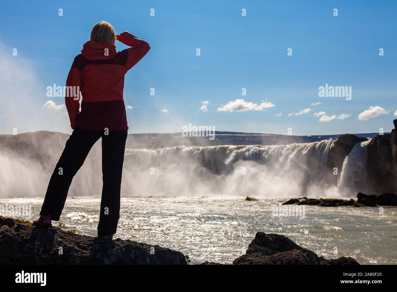 Frau touristische oder weibliche Wanderer stehen auf Felsen am Godafoss Wasserfall in Island suchen. Stockfoto