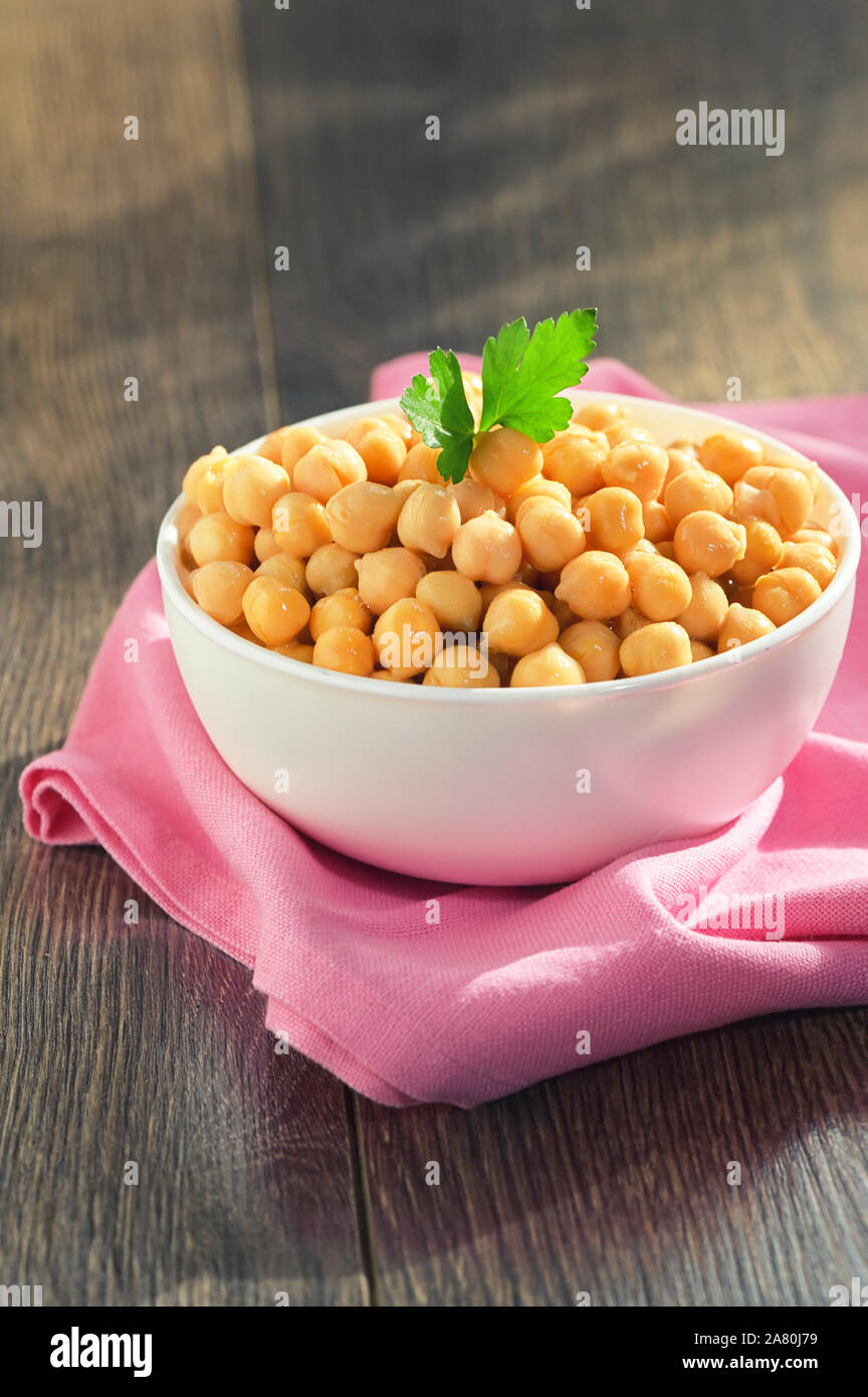 Gekochte Kichererbsen in Keramik Schüssel auf hölzernen Tisch Stockfoto