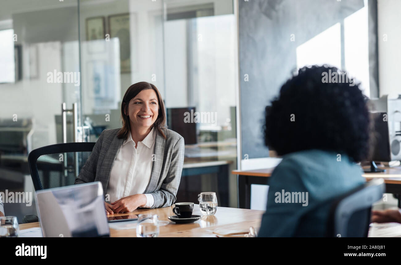 Zwei lächelnde Geschäftsfrau zusammen gesprochen um ein Büro Tabelle Stockfoto