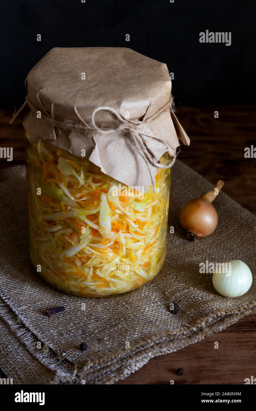 Fermentiertes Gemüse. Mit Karotten in einem Glas auf einem dunklen Hintergrund Sauerkraut. Vertikale Ausrichtung Stockfoto