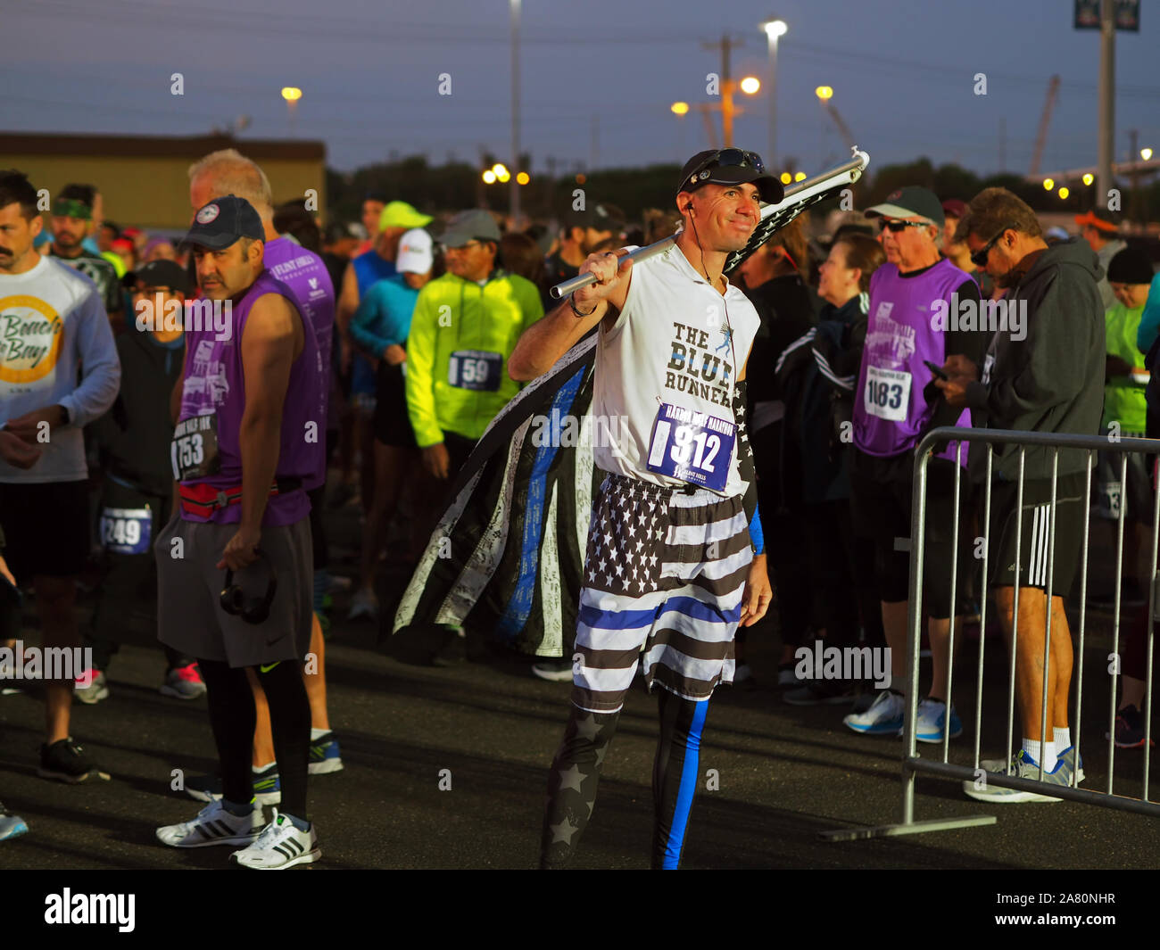 Mann hält Version der "Thin Blue Line" der amerikanischen Flagge, während für den Start der 2019 Hafen Halbmarathon in Corpus Christi, Texas USA warten. Stockfoto