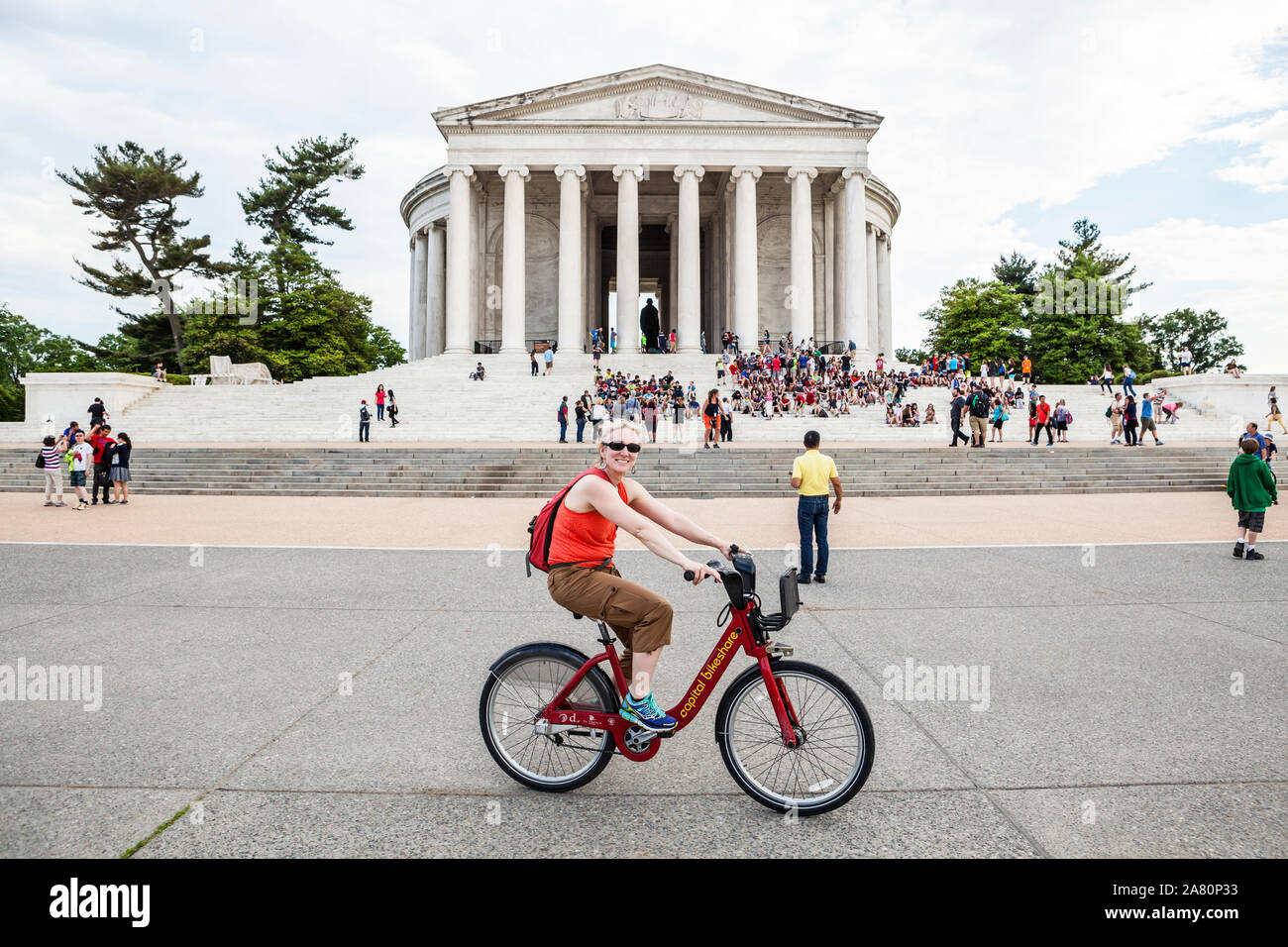 Eine lächelnde Frau mittleren Alters mit dem Fahrrad Teile Fahrrad vor Das Jefferson Memorial, Washington, D.C., USA. Stockfoto