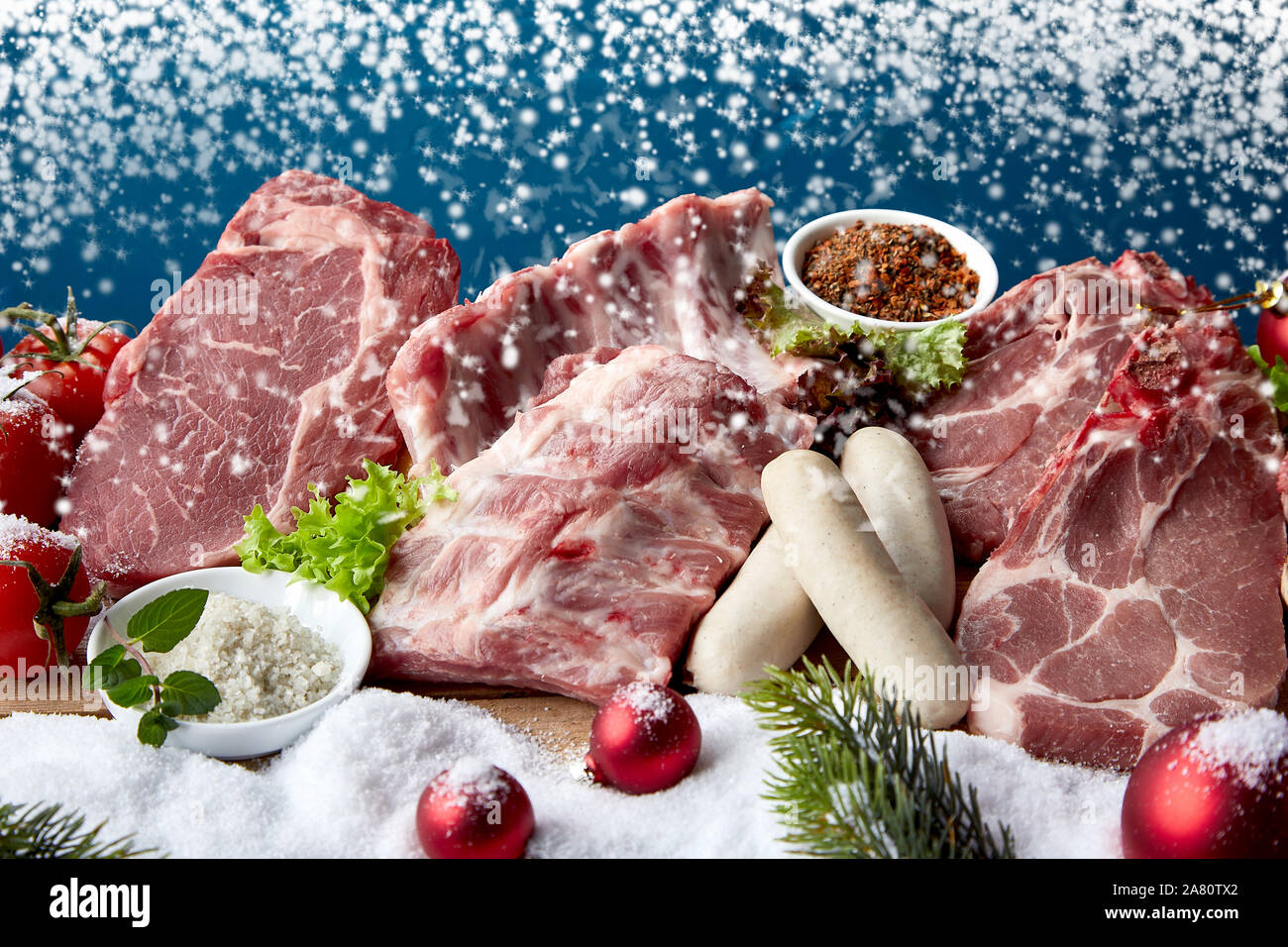 Rohes Fleisch und rohe Würste Layout mit Schnee und Weihnachtsschmuck, im Winter urlaub Zutaten zum Kochen Konzept kombiniert Stockfoto