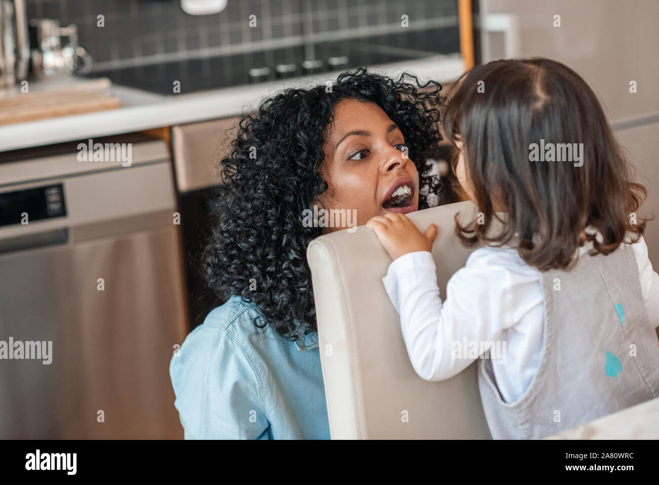 Lächelnd Mama spielen peekaboo mit ihrer süßen kleinen Tochter Stockfoto