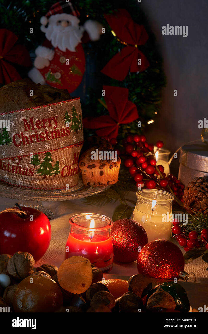 Weihnachten und das Neue Jahr im Licht der Kerzen mit Süßigkeiten und Obst, rot und gold Ornamente spezifisch für diese Termine auf einem weißen Faden Tischdecke bac Stockfoto