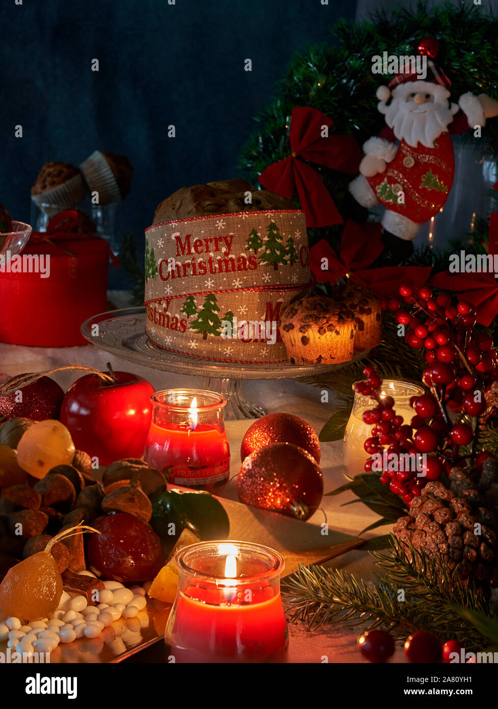 Weihnachten und das Neue Jahr im Licht der Kerzen mit Süßigkeiten und Obst, rot und gold Ornamente spezifisch für diese Termine auf einem weißen Faden Tischdecke bac Stockfoto