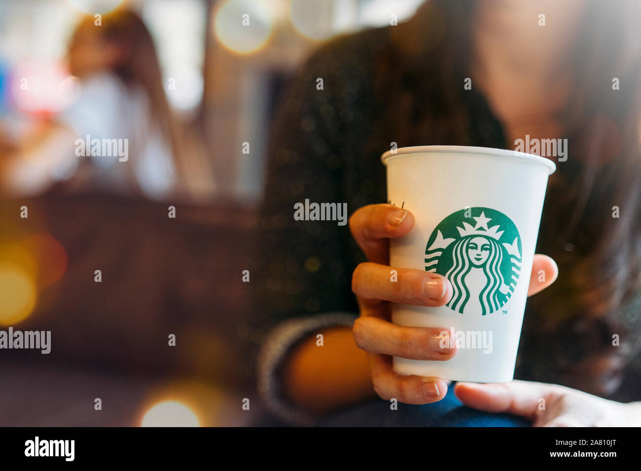New York, USA - November 5, 2019: Nahaufnahme einer Frau trinkt ein hohes Starbucks Kaffee im Starbucks Coffee Shop mit karottenkuchen. Starbucks ist der NPV Stockfoto